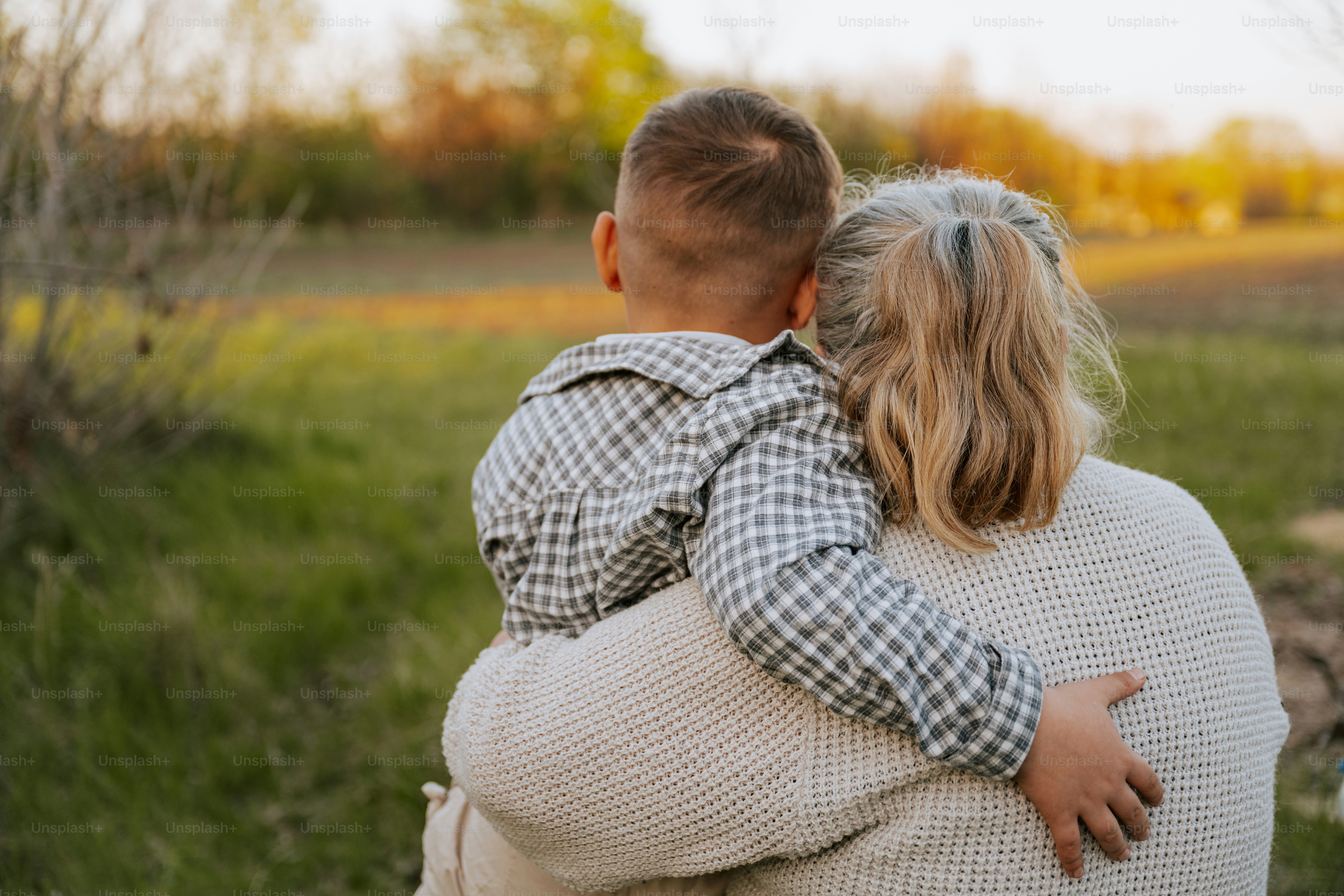 Die Großmutter hält ein Kind, während sie auf das Feld schaut.