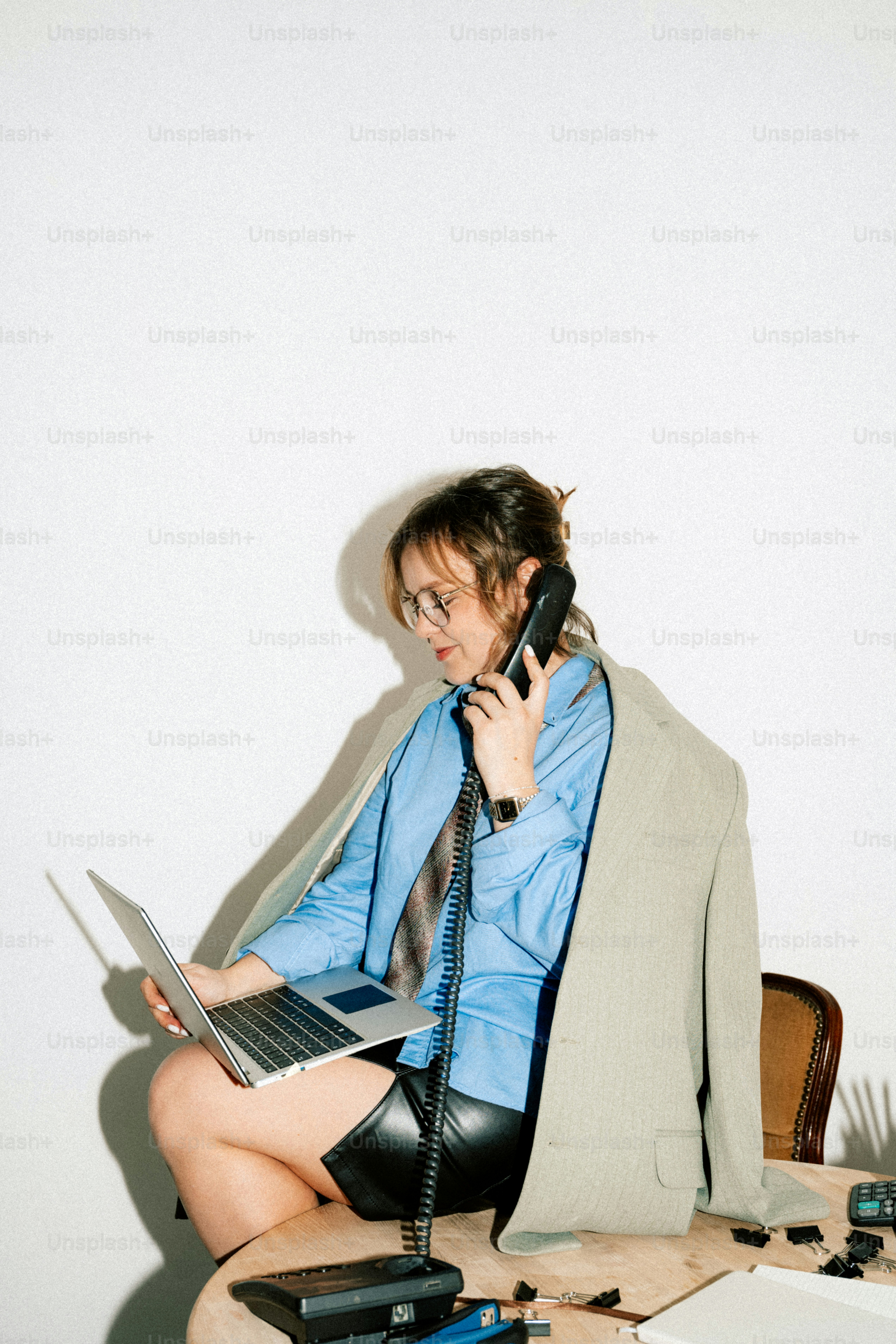 A woman works on a laptop while using the phone. photo – Leadership ...