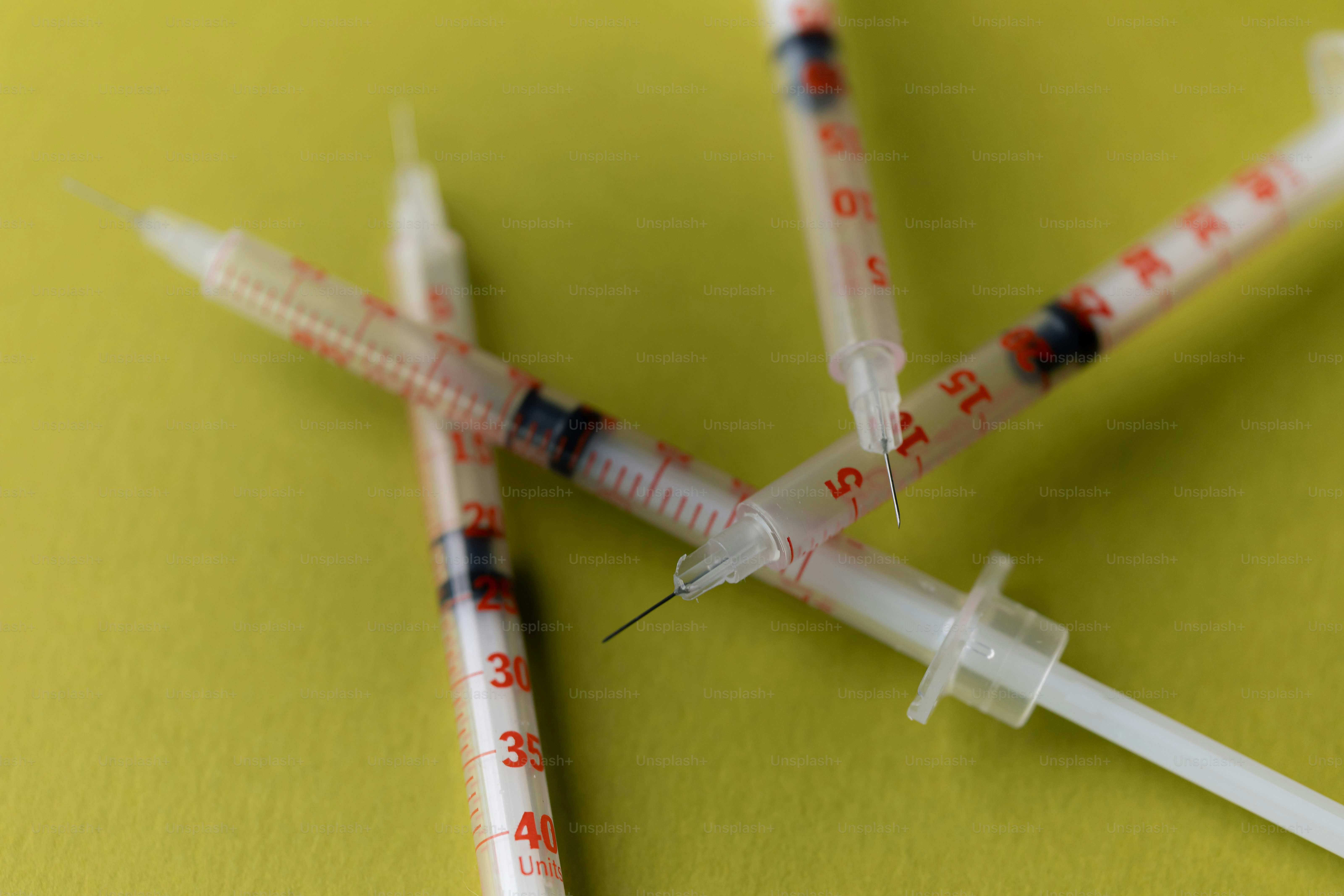 Las jeringas están esparcidas sobre una superficie verde brillante.