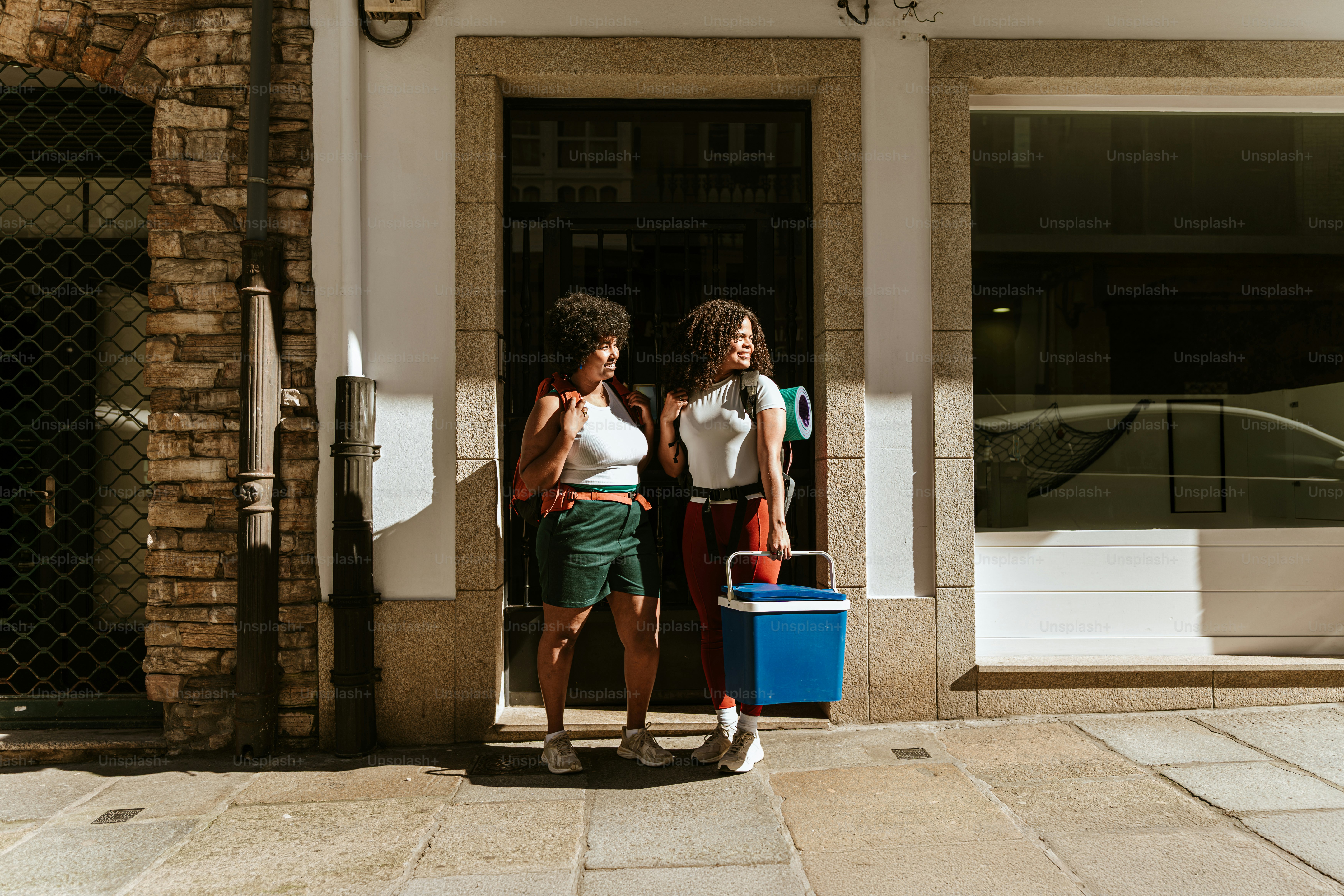 Two women stand by a door with a cooler.