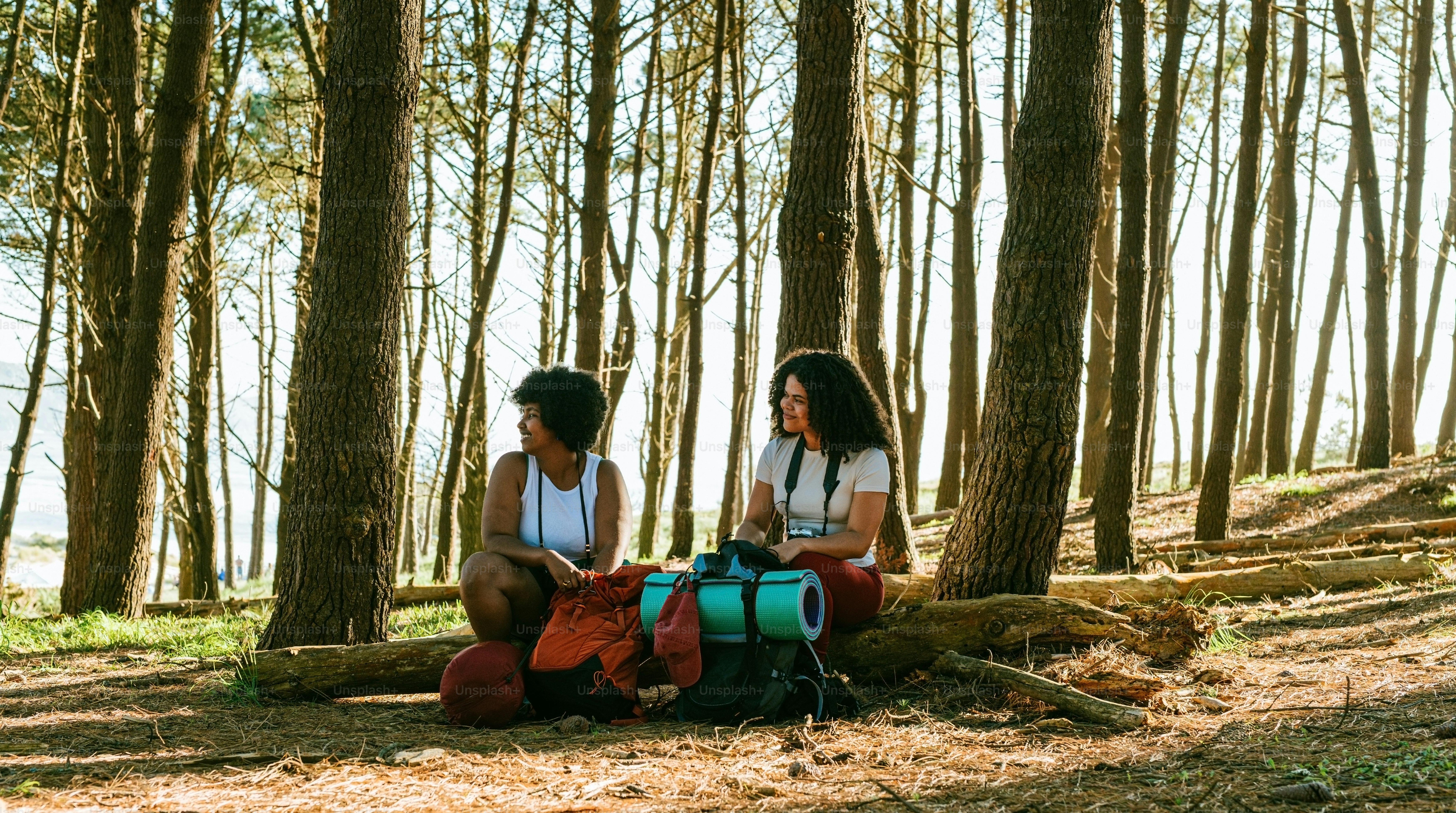 Two women rest during a hike in the woods.