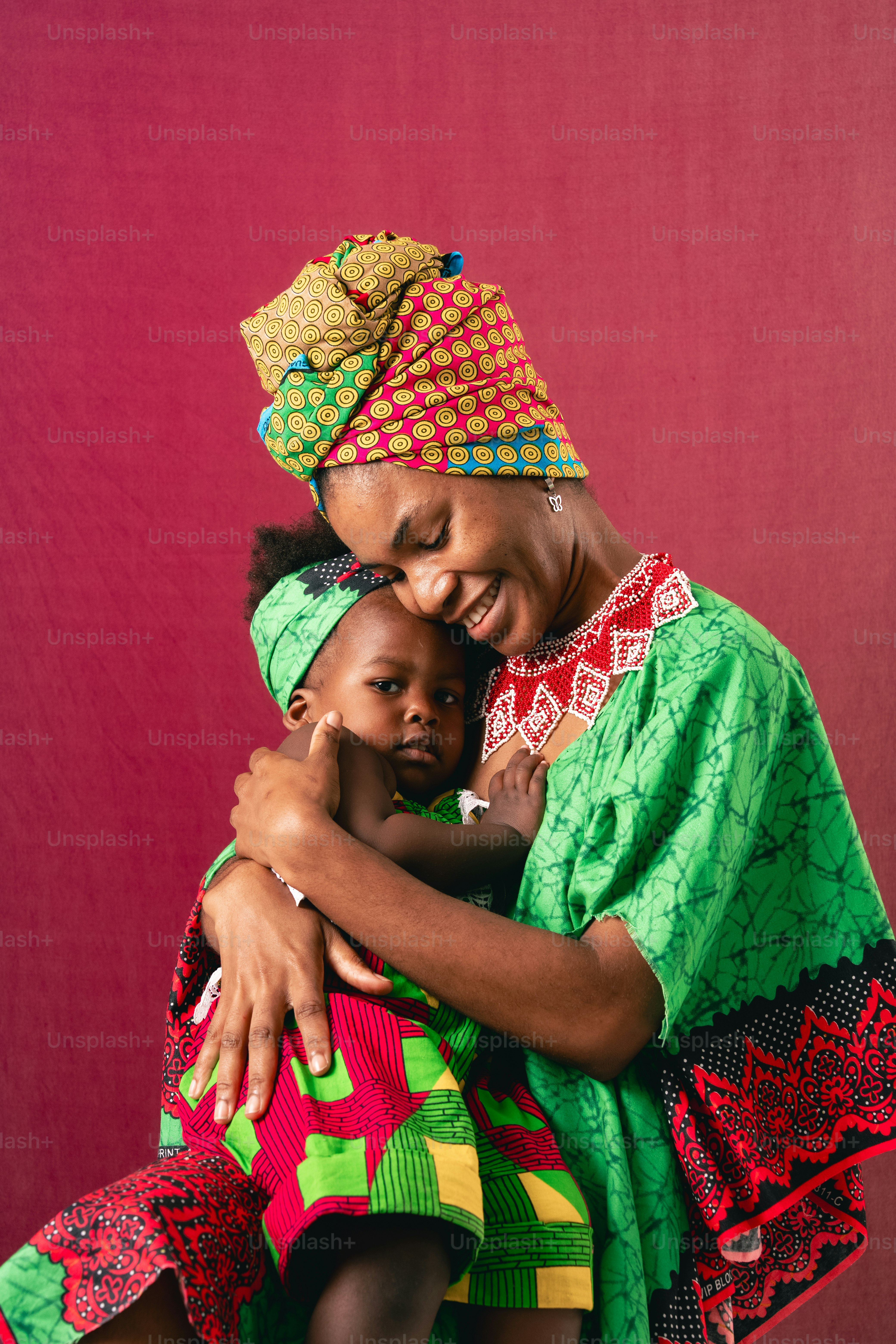 Mother and baby embrace, both in colorful outfits.