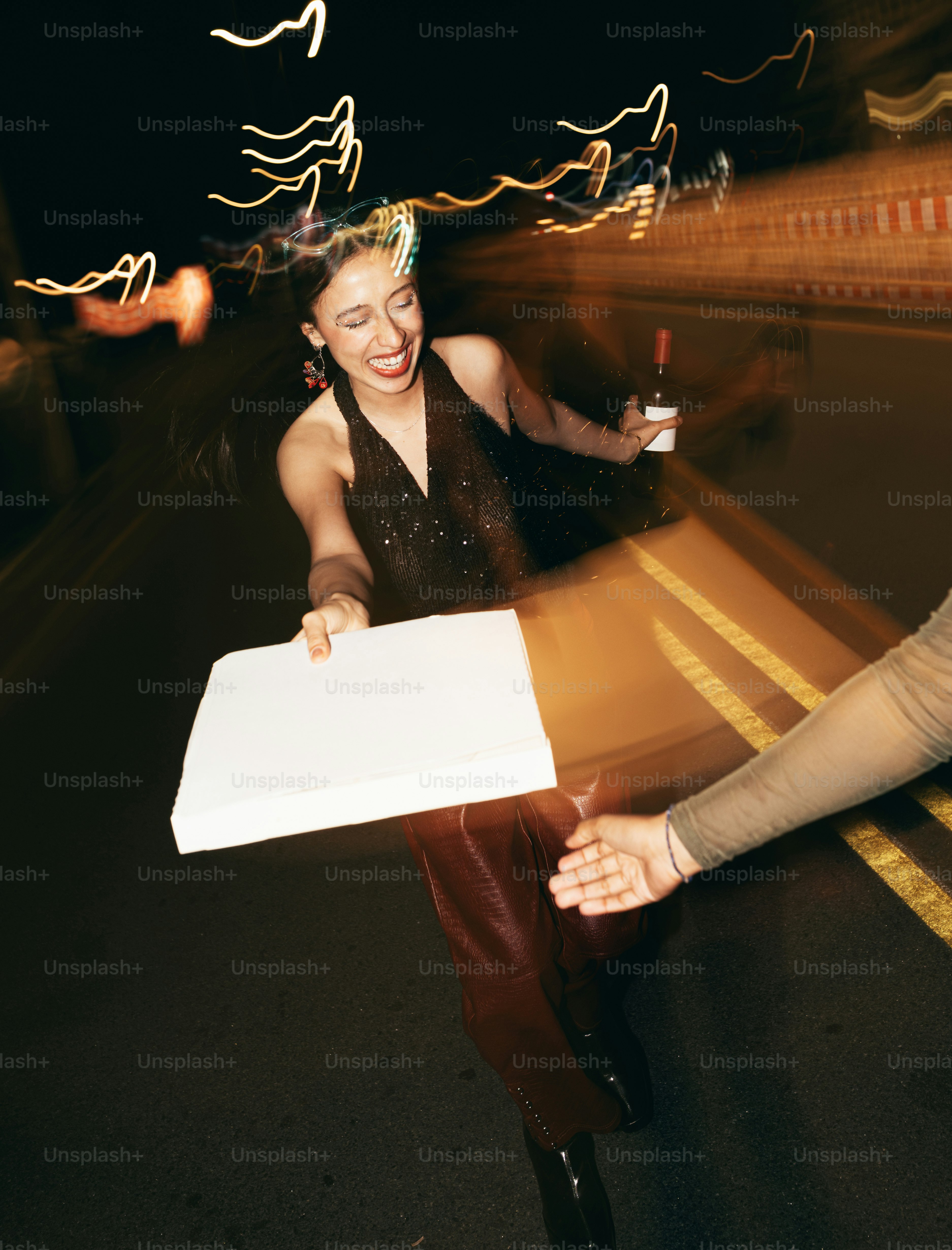 A woman grabs a pizza box with a drink.