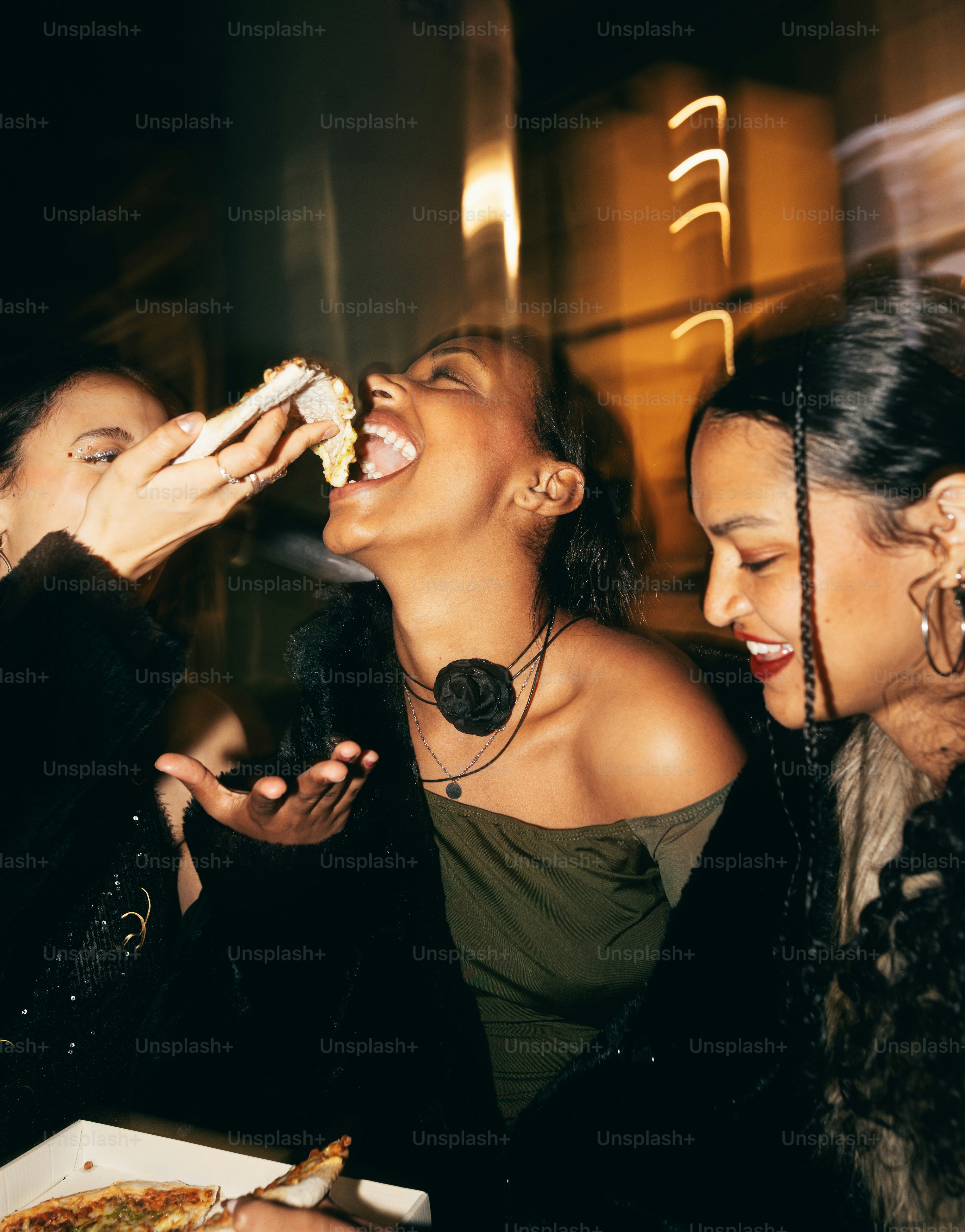 Friends enjoy pizza and laughter at night.