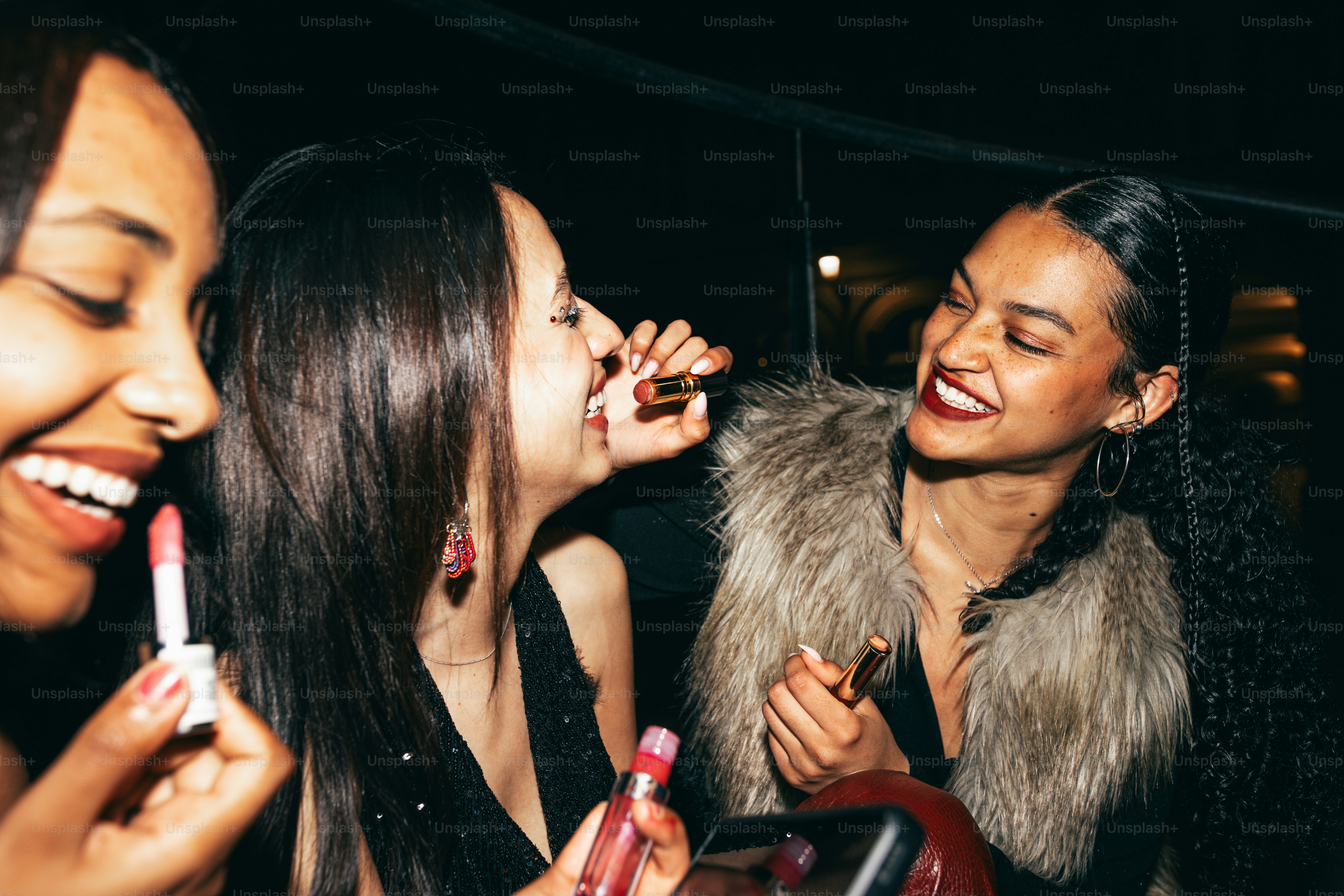 Friends are laughing and applying lipstick.