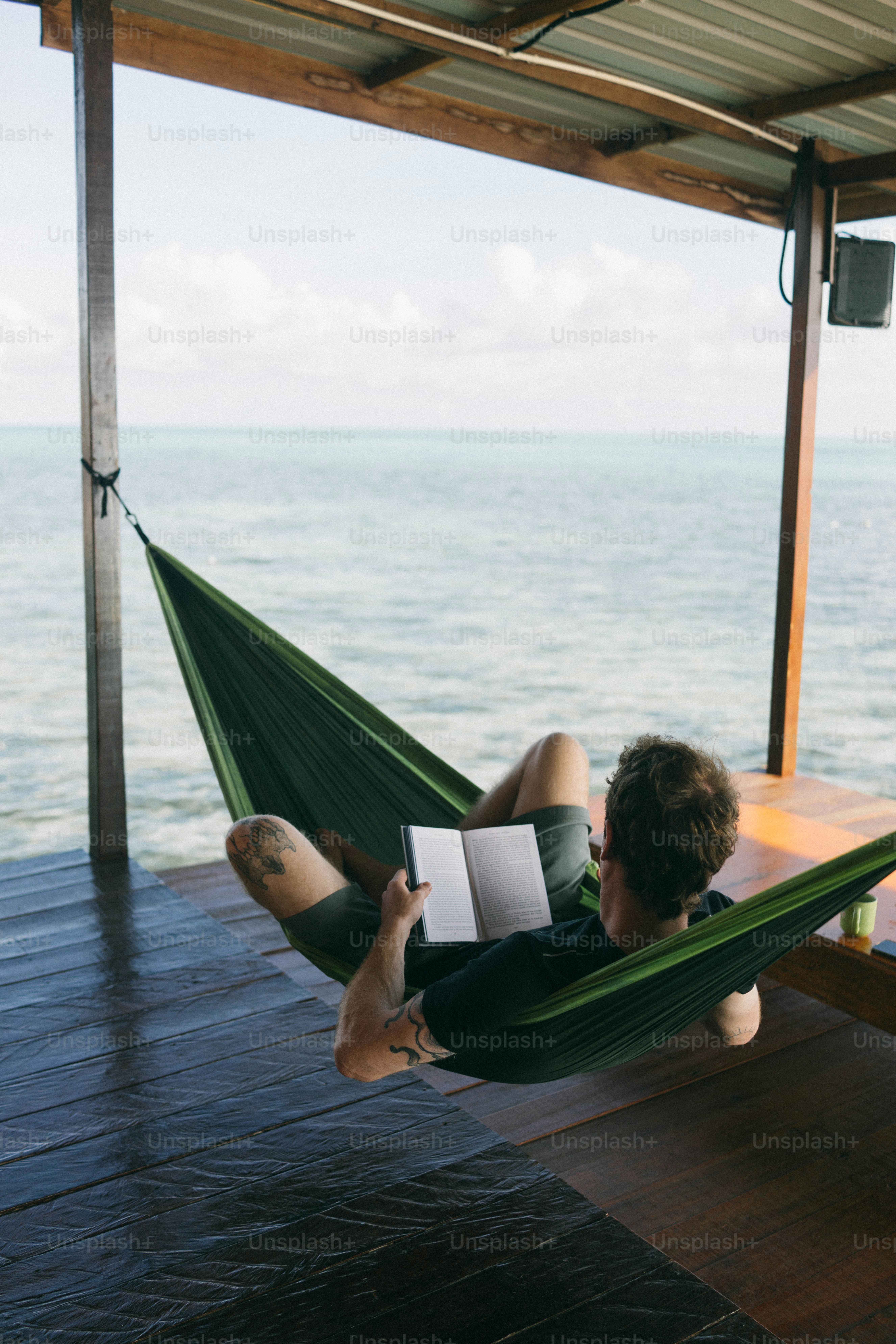 Man relaxes in a hammock, reading a book. photo – Travel Image on Unsplash