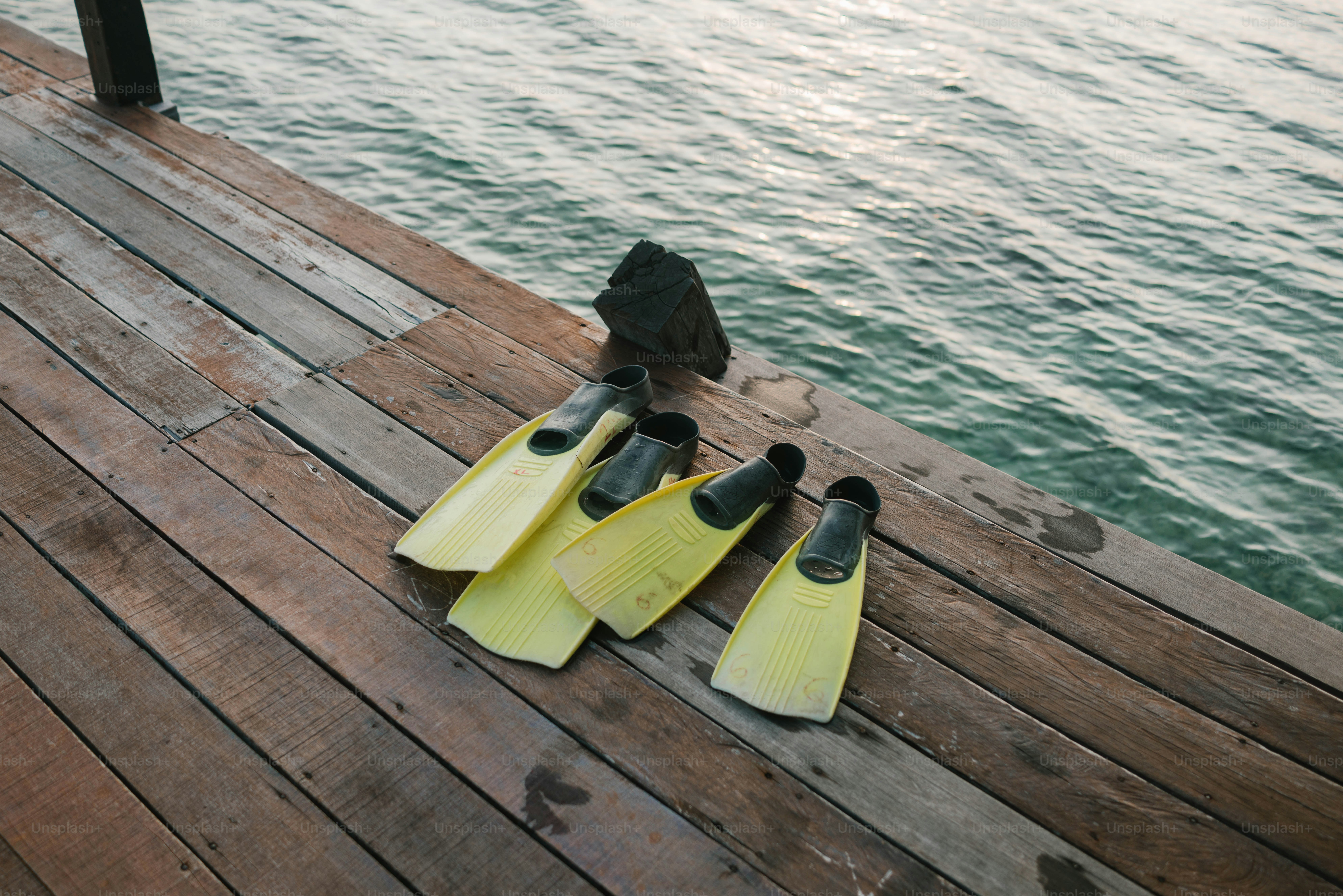 Flippers are on a dock next to the water.