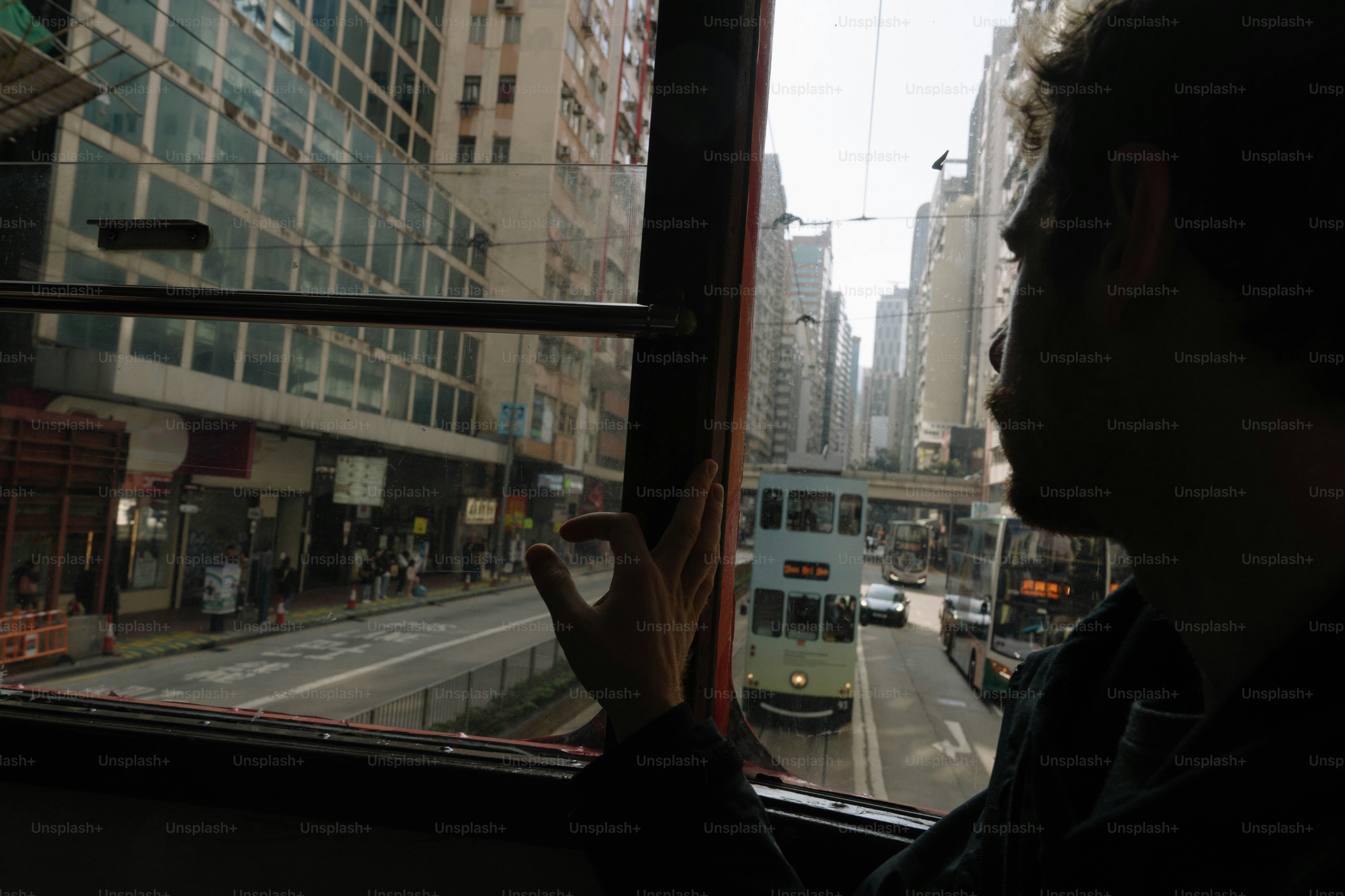 Man looks out of a tram window at city.