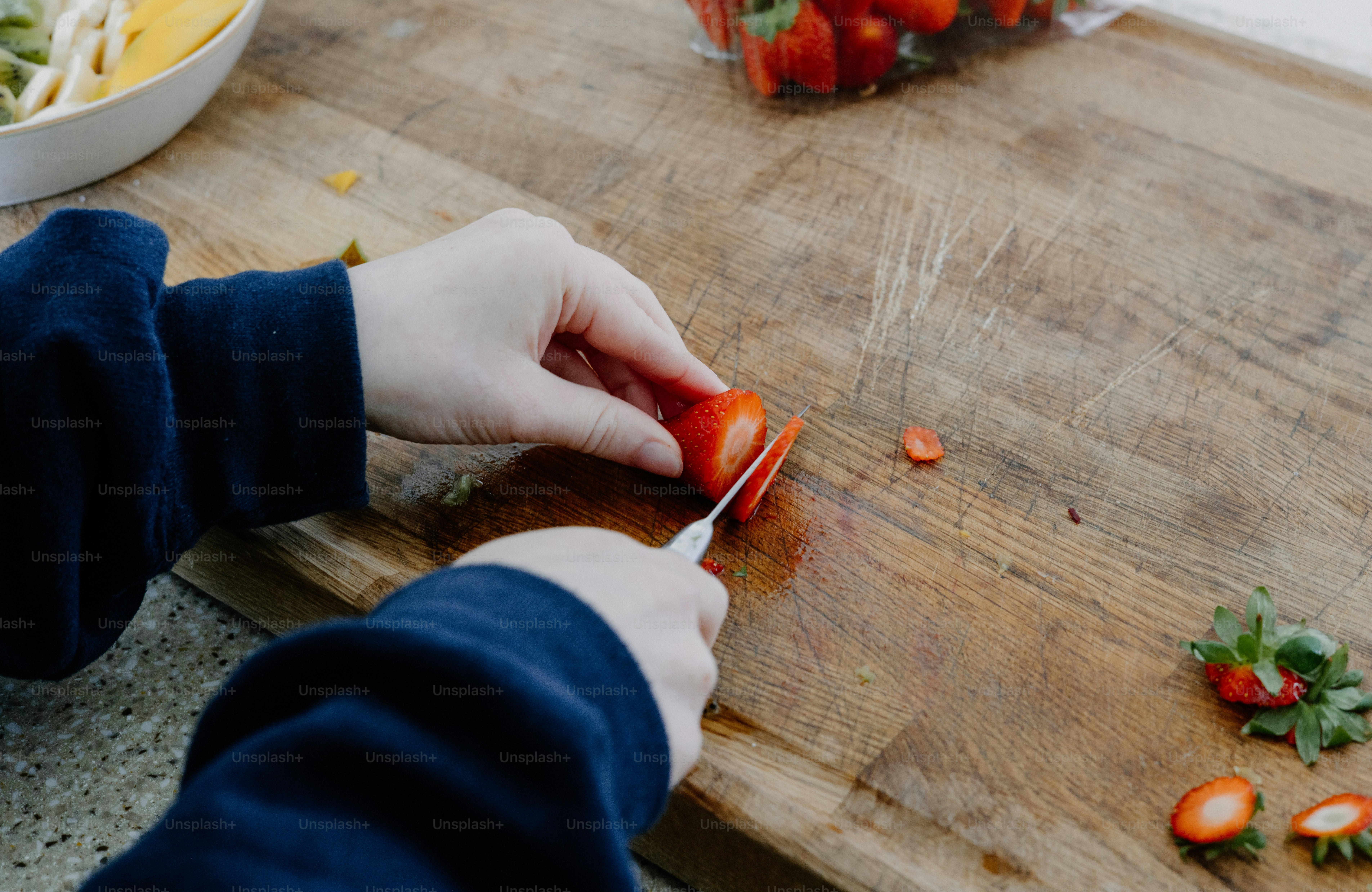 누군가 나무판에 딸기를 자르고 있습니다.