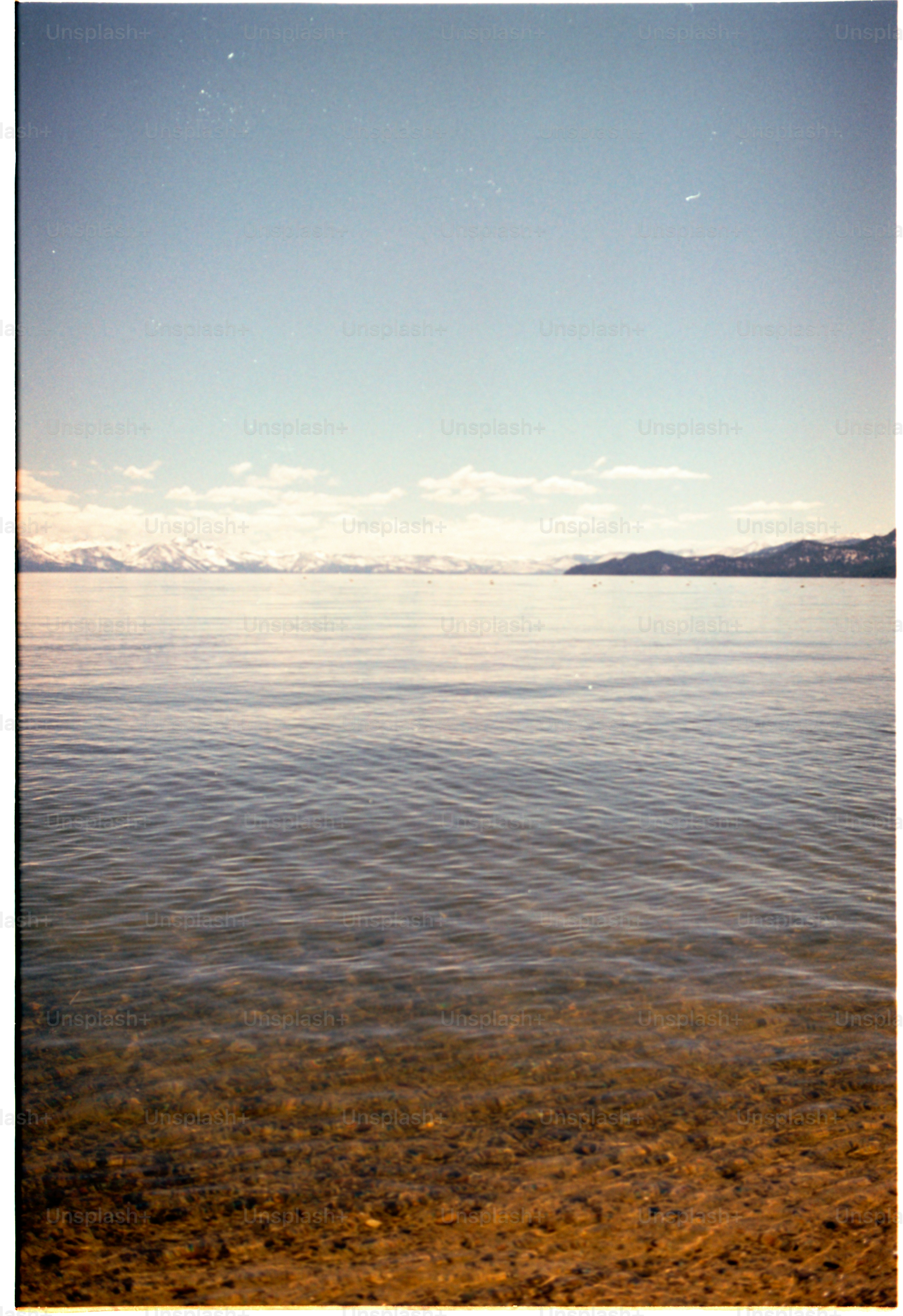 Calm lake waters with snowy mountains in the distance.