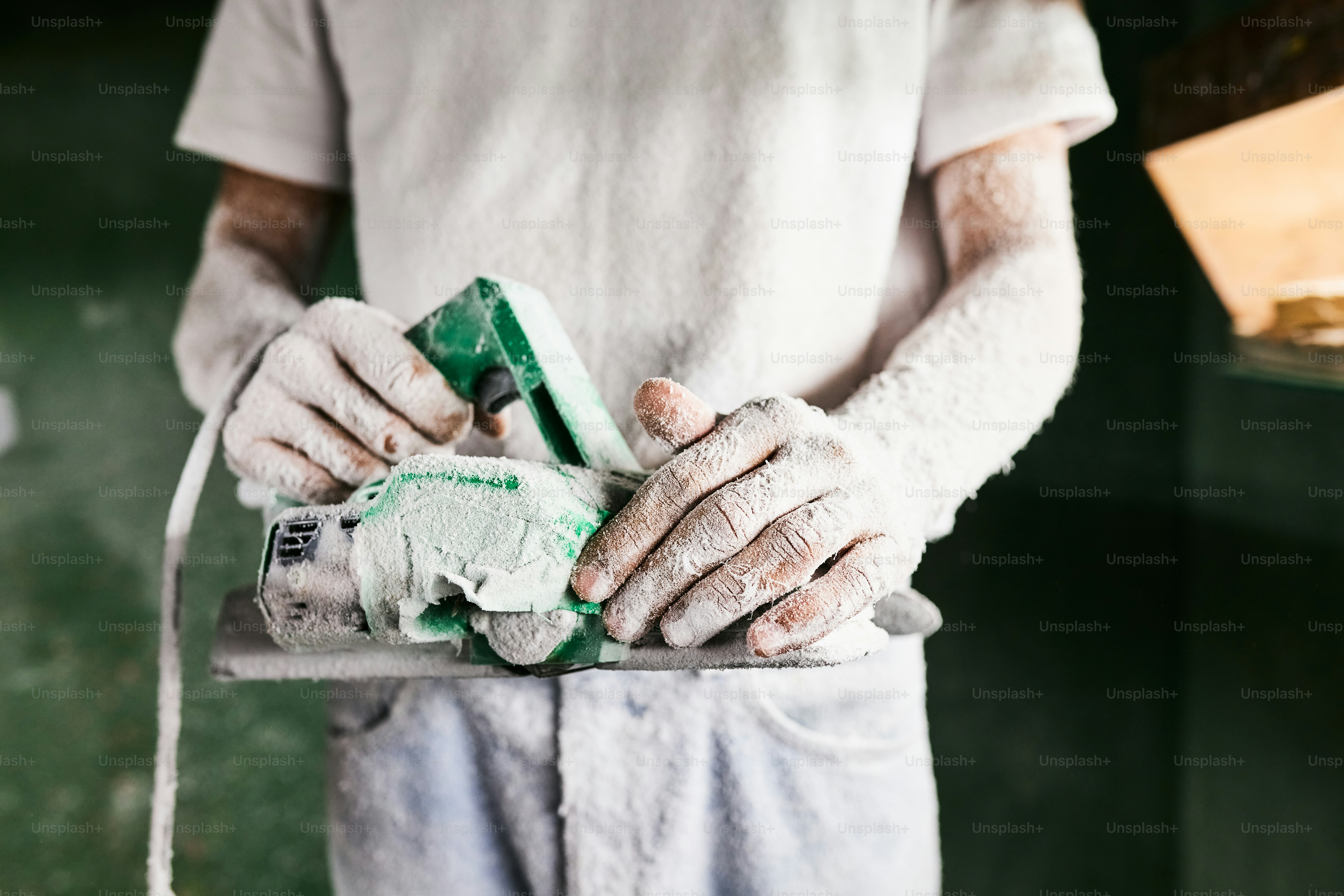 A plasterer works with gloves and a tool.