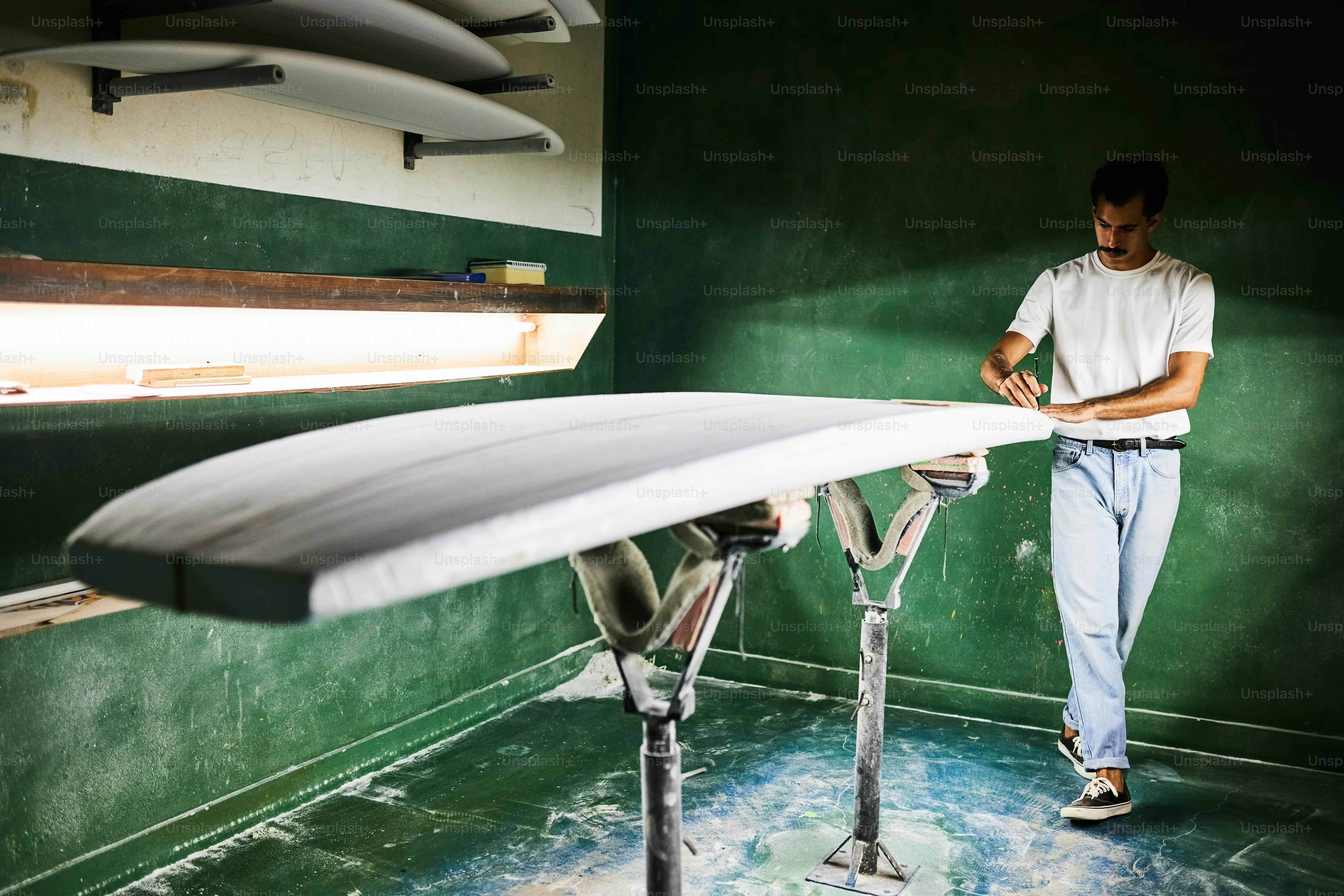 A craftsman shaping a surfboard in a workshop.