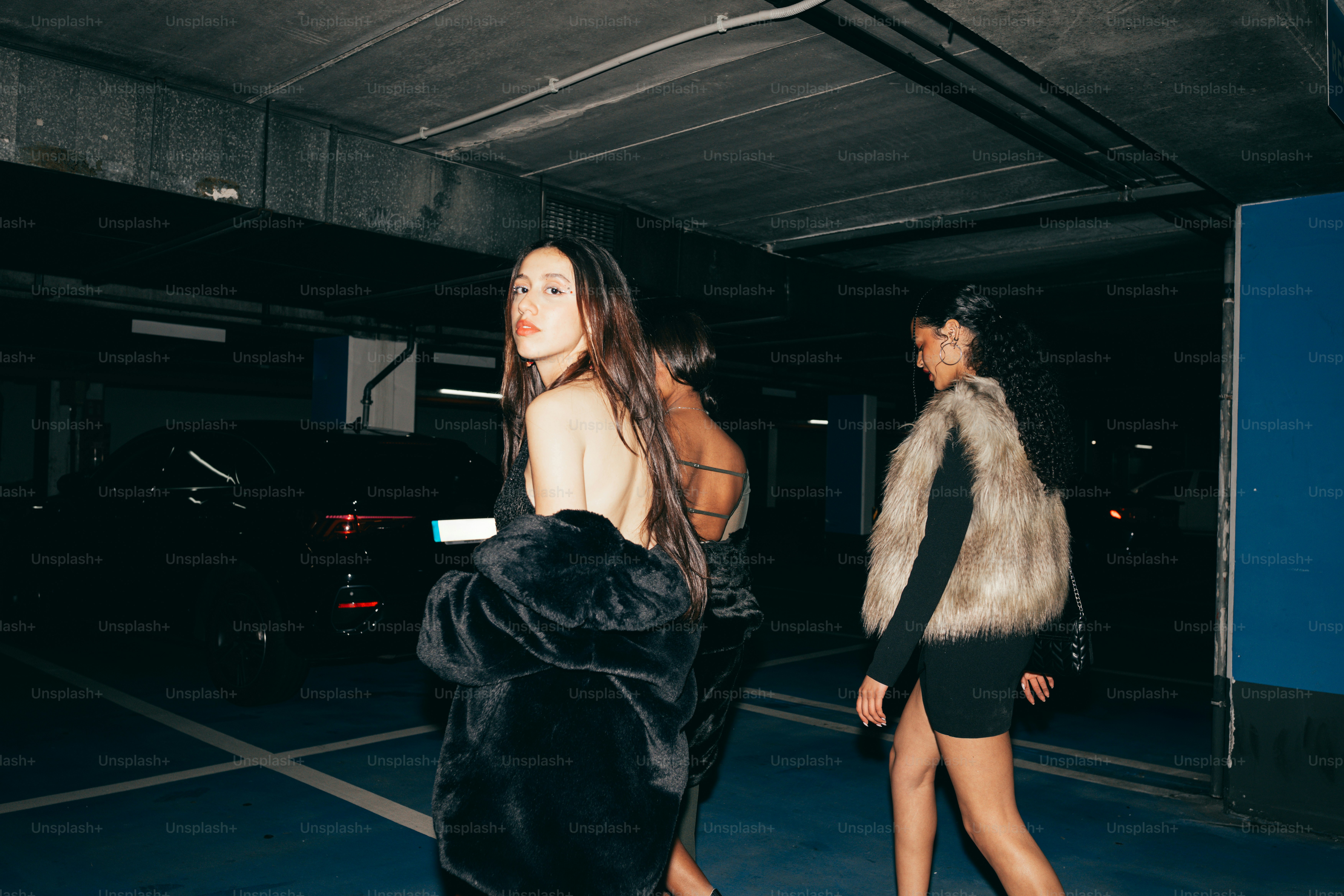 Stylish women walk through a dark parking garage.