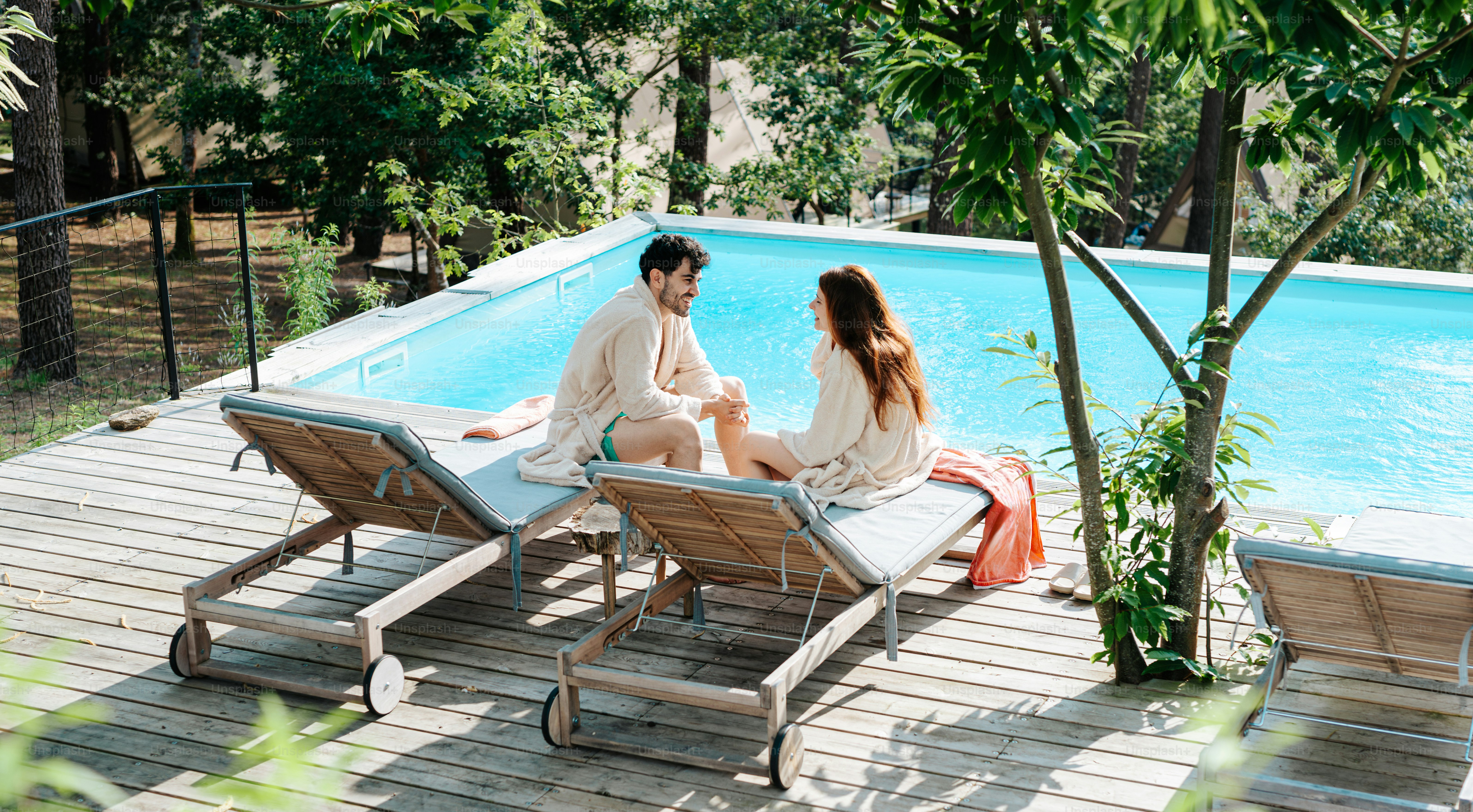 A couple relaxes beside a swimming pool.