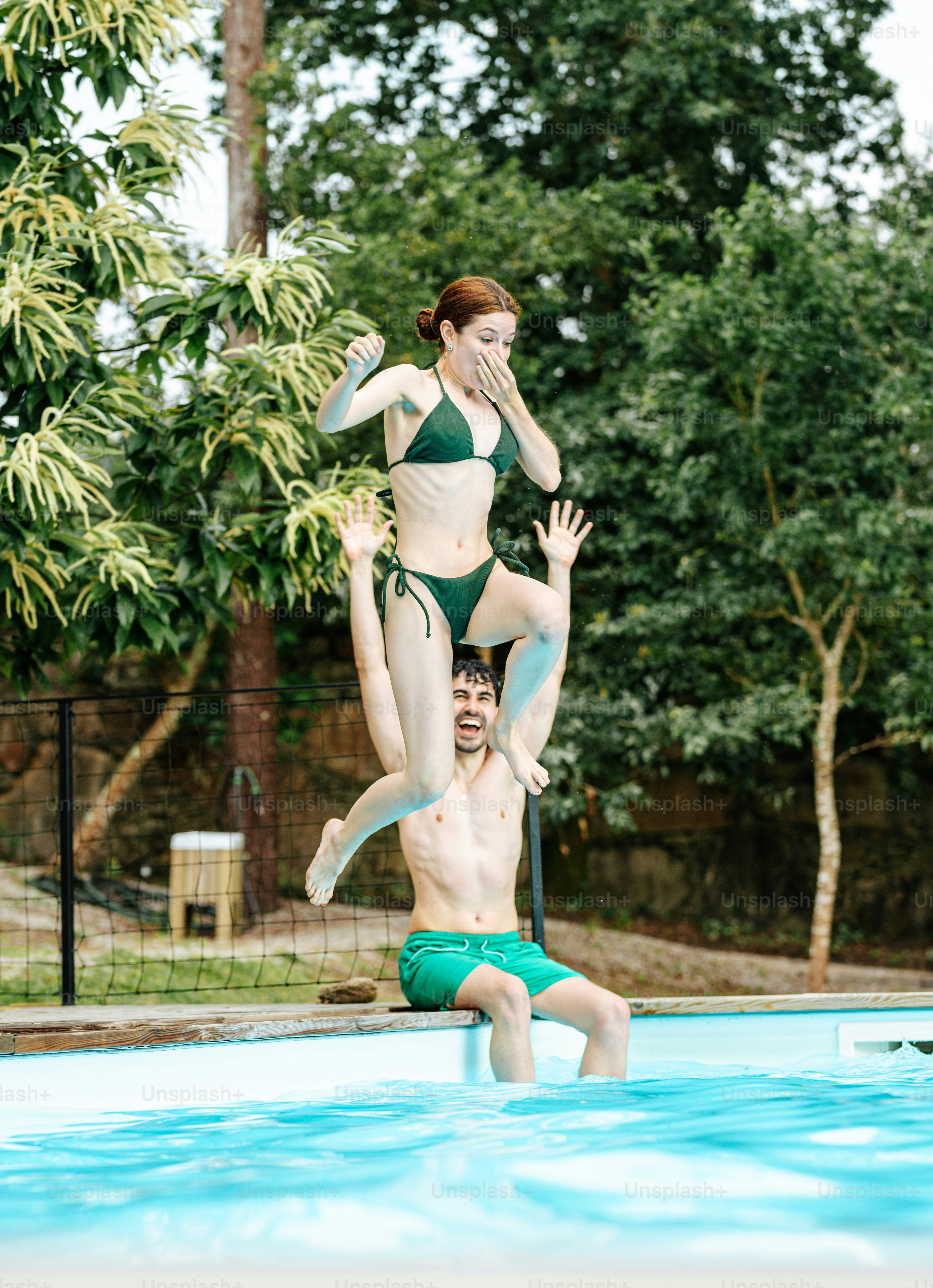 A man lifts a woman into the pool.