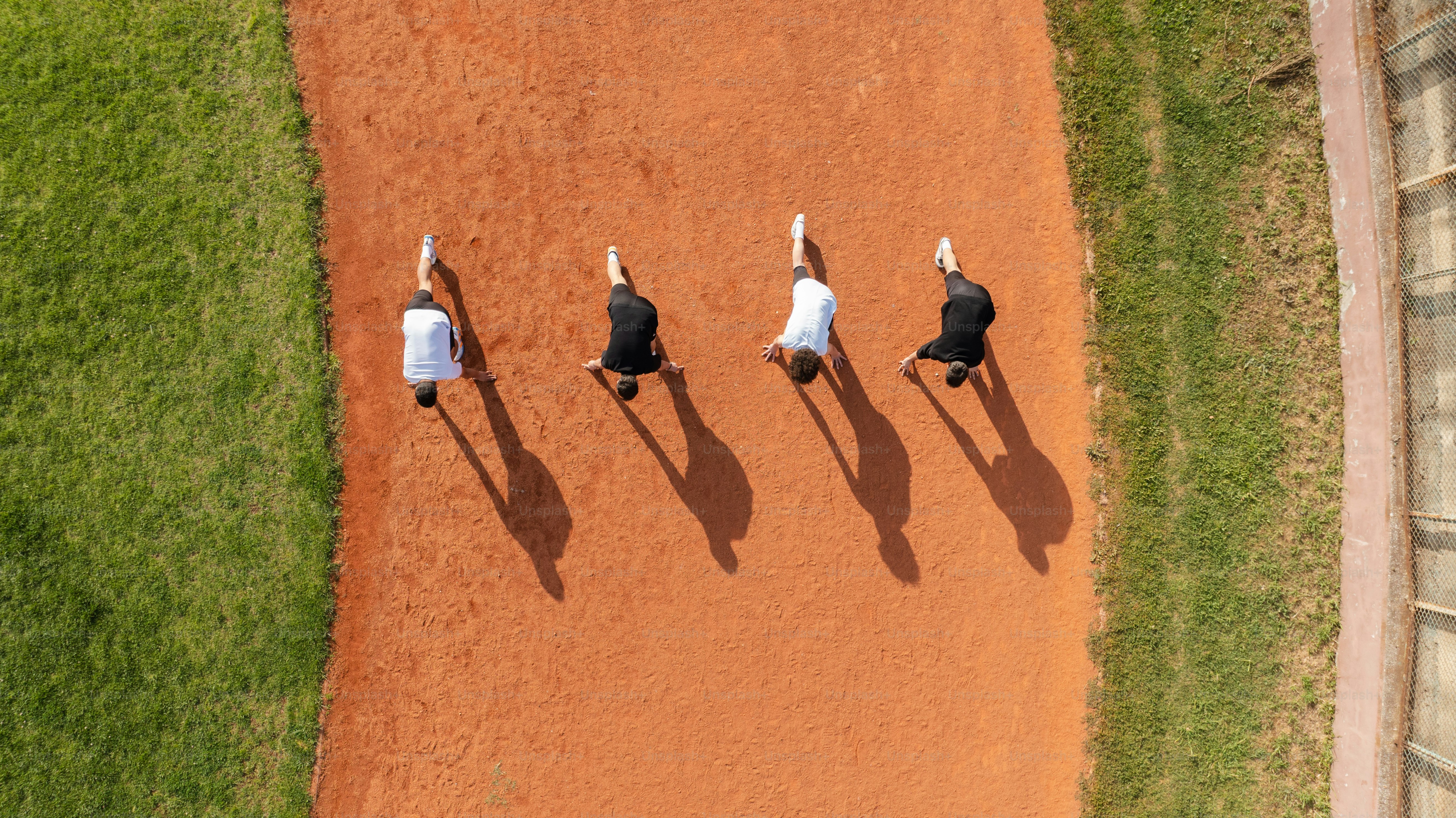 Four people are kneeling on a baseball field.
