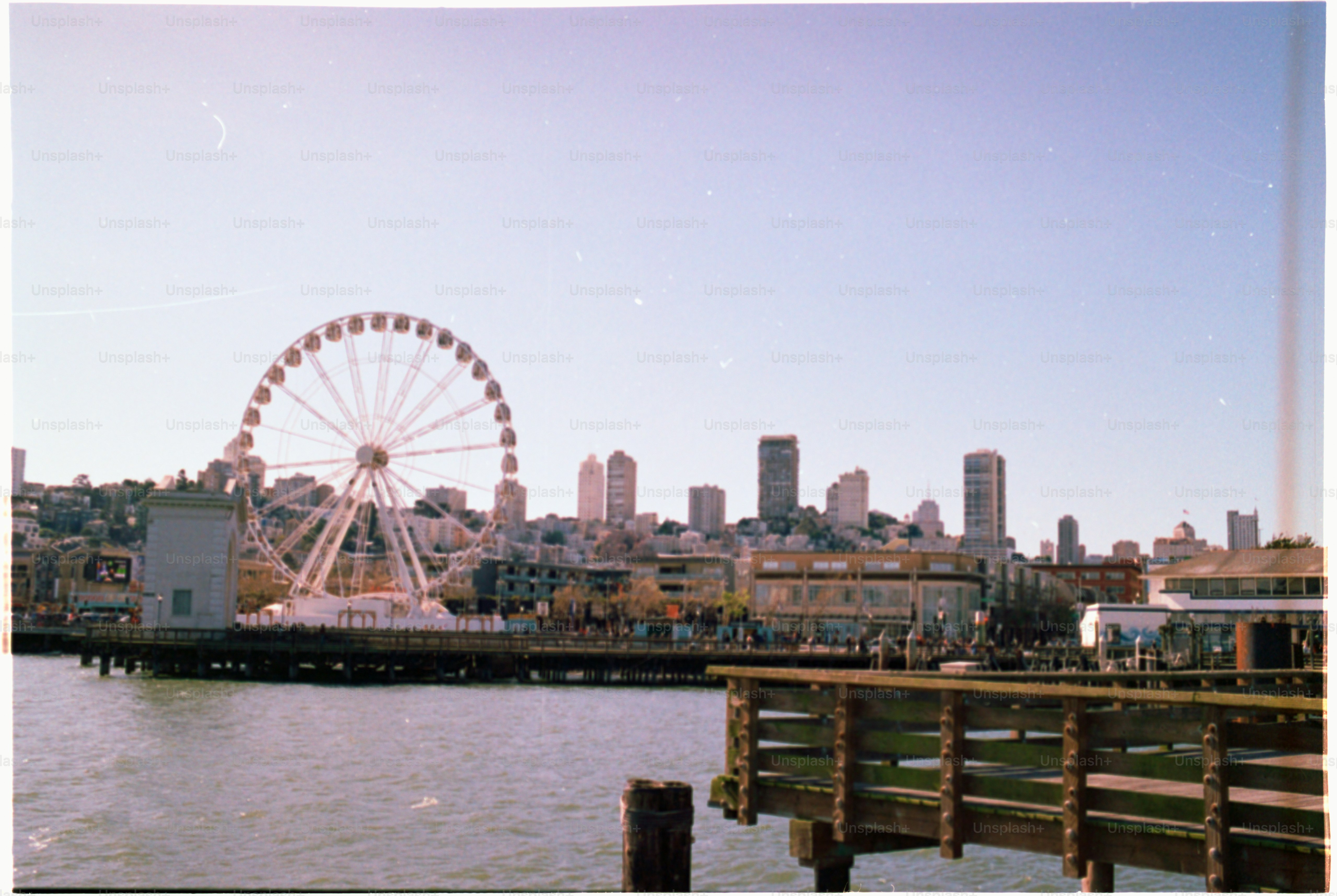 Ferris wheel and city skyline overlook the water.