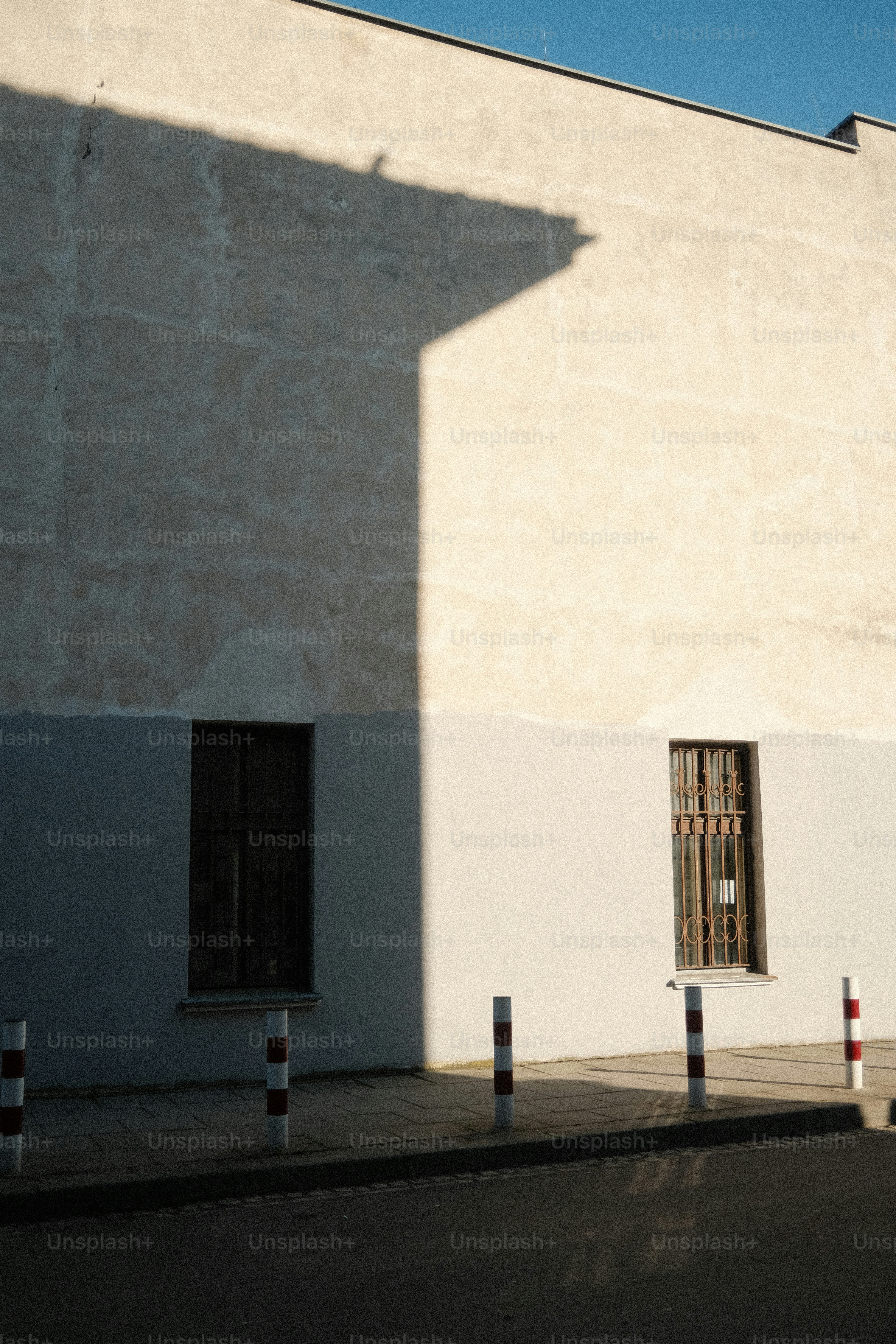 Shadows fall on a building with barred windows.