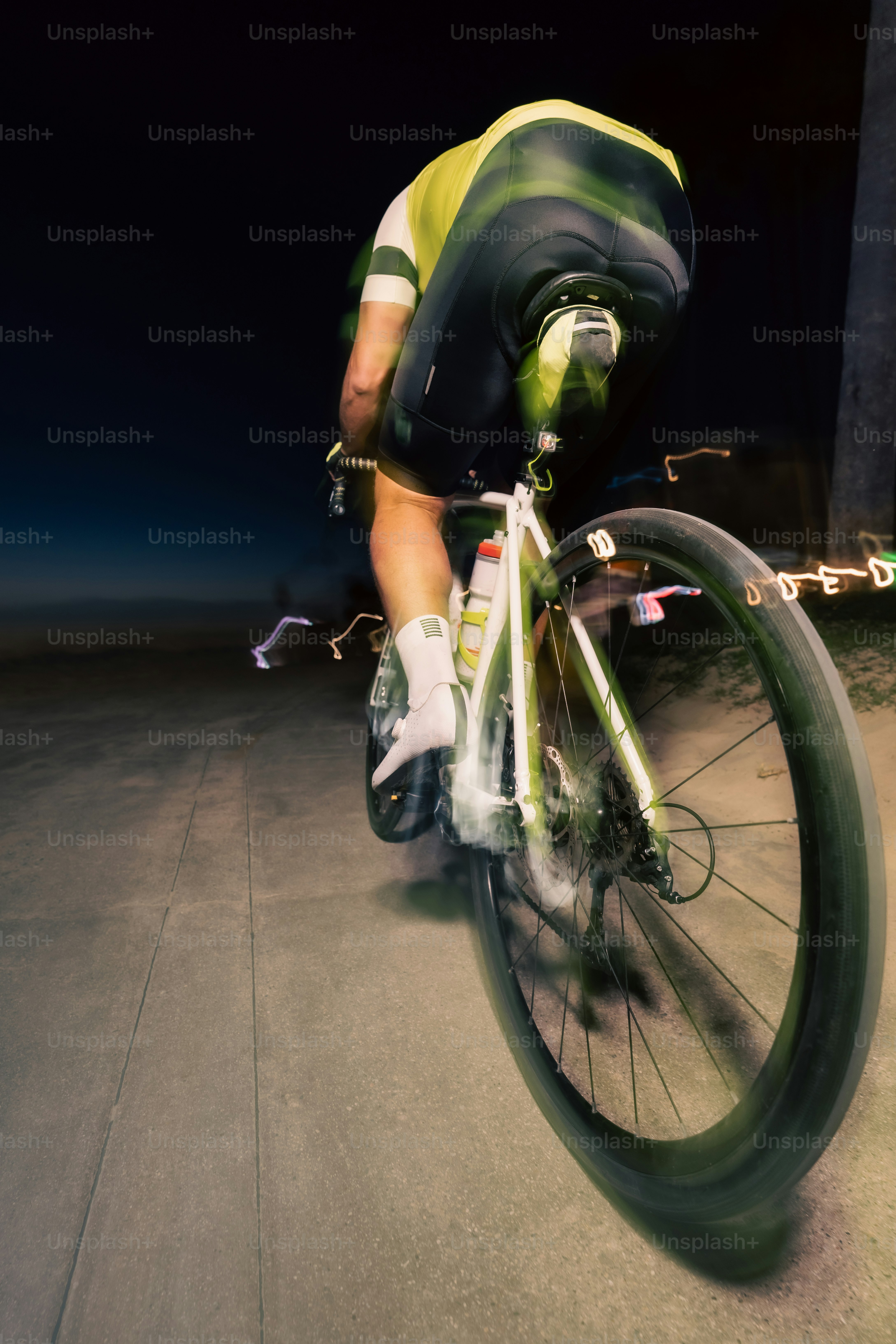 Cyclist rides bicycle at night, blurred for speed.