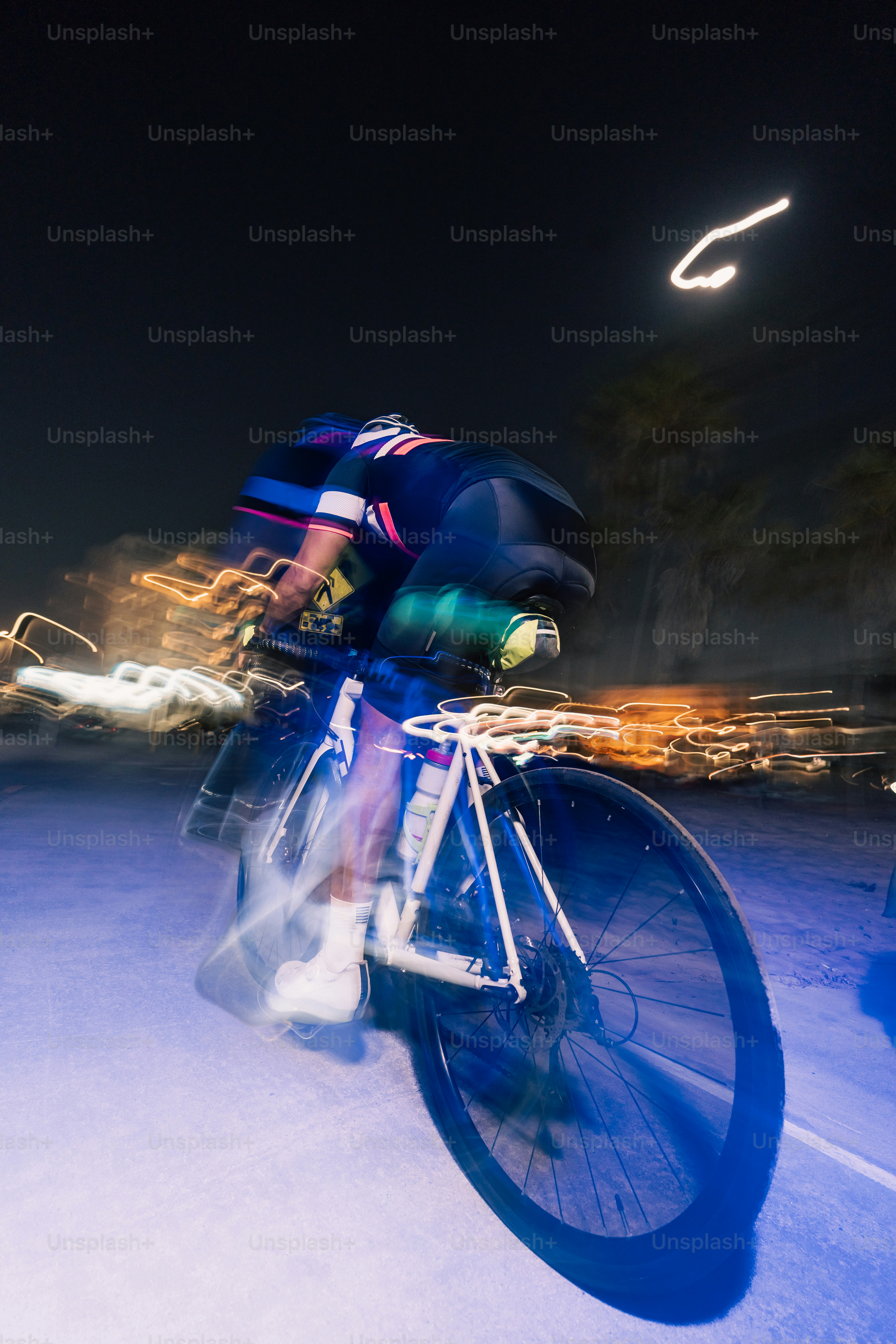 サイクリストは夜の道路をぼかしでスピードを上げます。