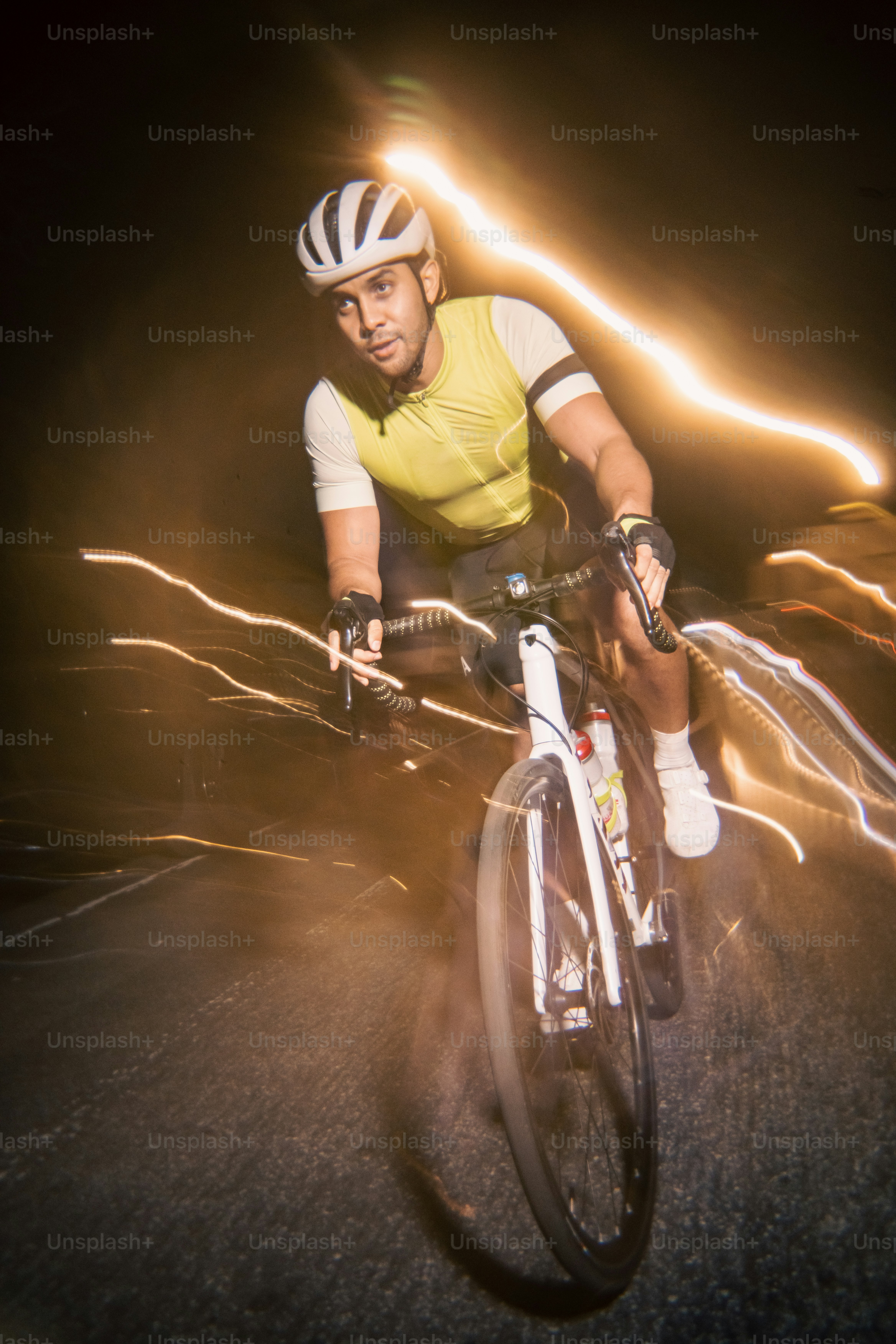 サイクリストは夜に光の筋に乗っています。