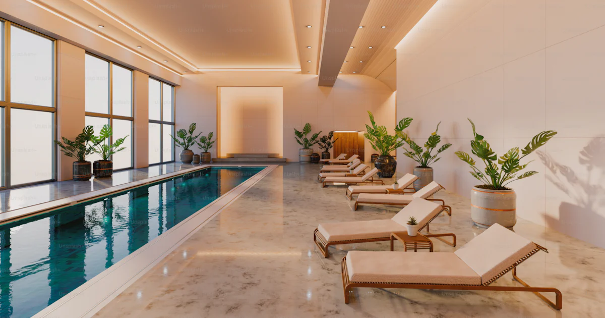 Indoor pool area with lounge chairs and plants. photo – Architecture ...