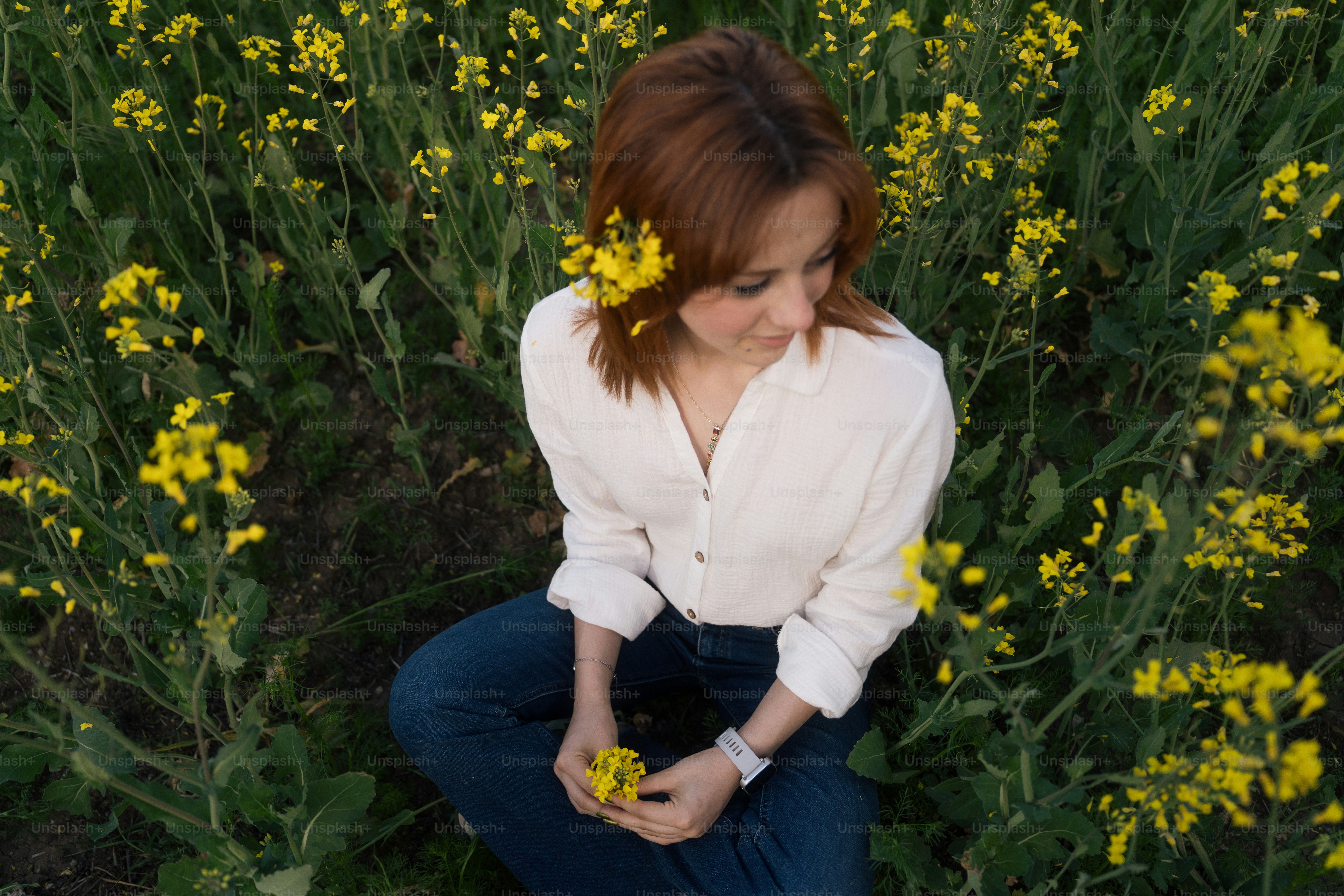 A woman sits in a field of yellow flowers