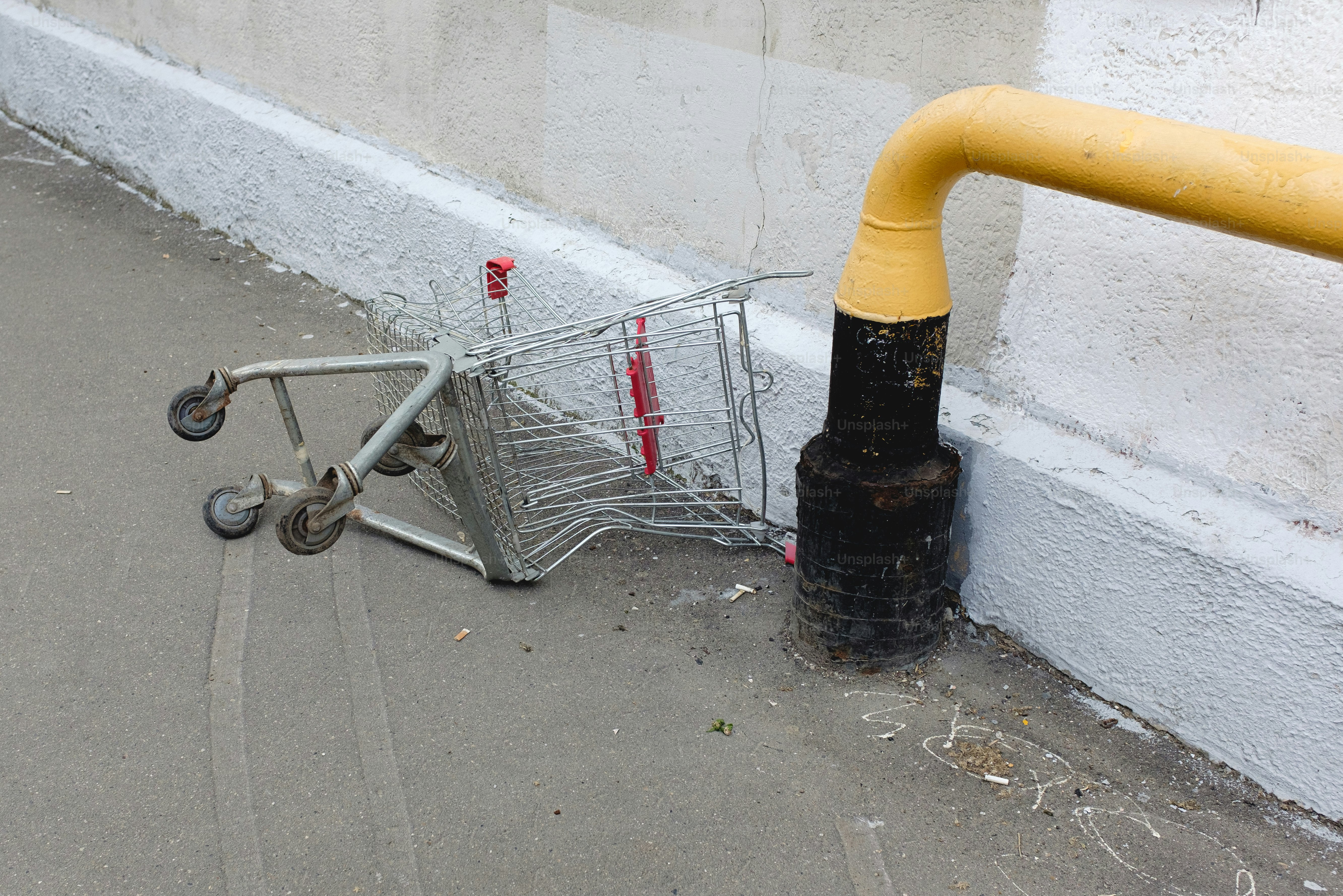 Un carrito de la compra está apoyado en una tubería amarilla.
