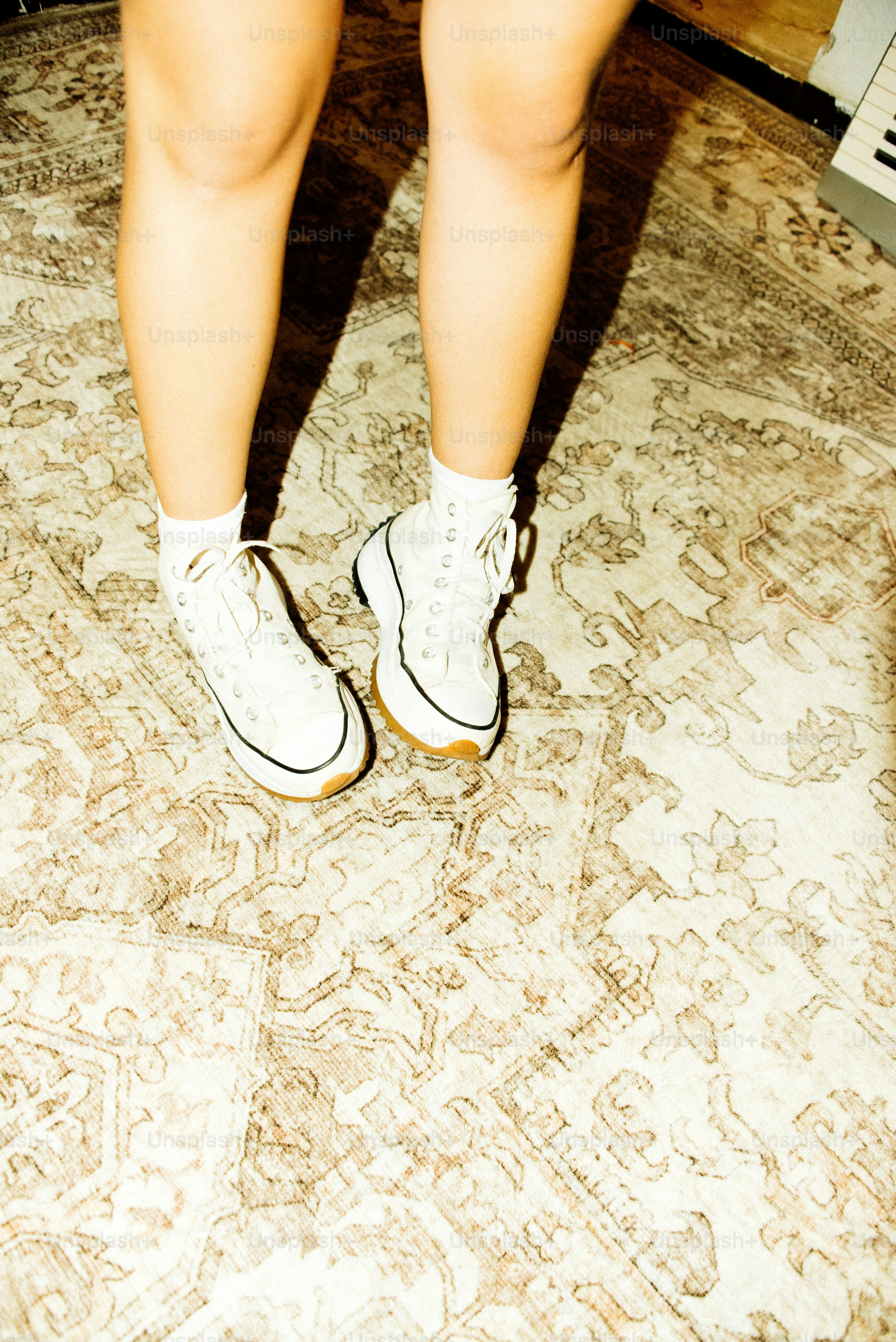 White sneakers and socks standing on a patterned rug. photo – Film ...