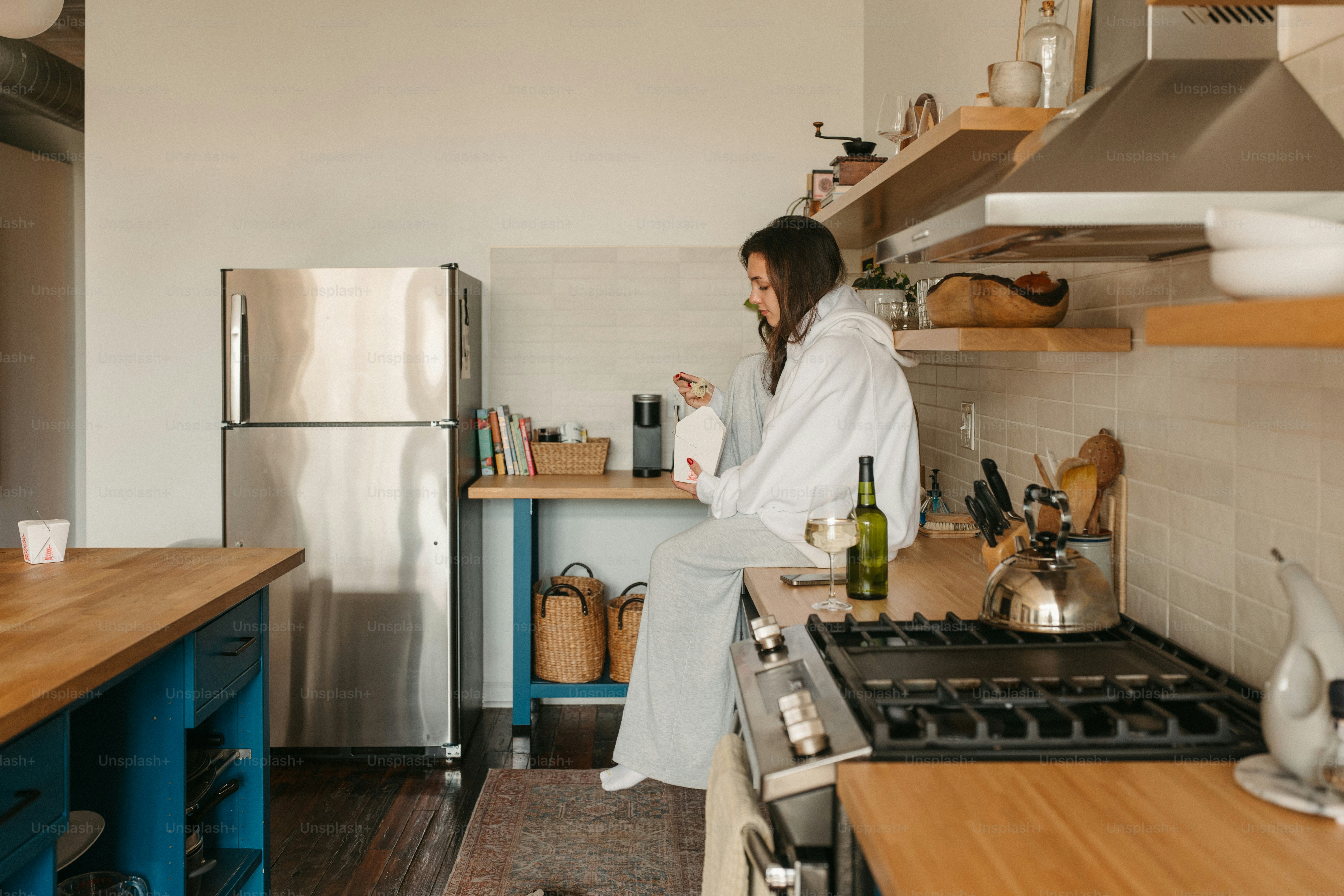 Woman relaxes on her kitchen counter with a beverage.