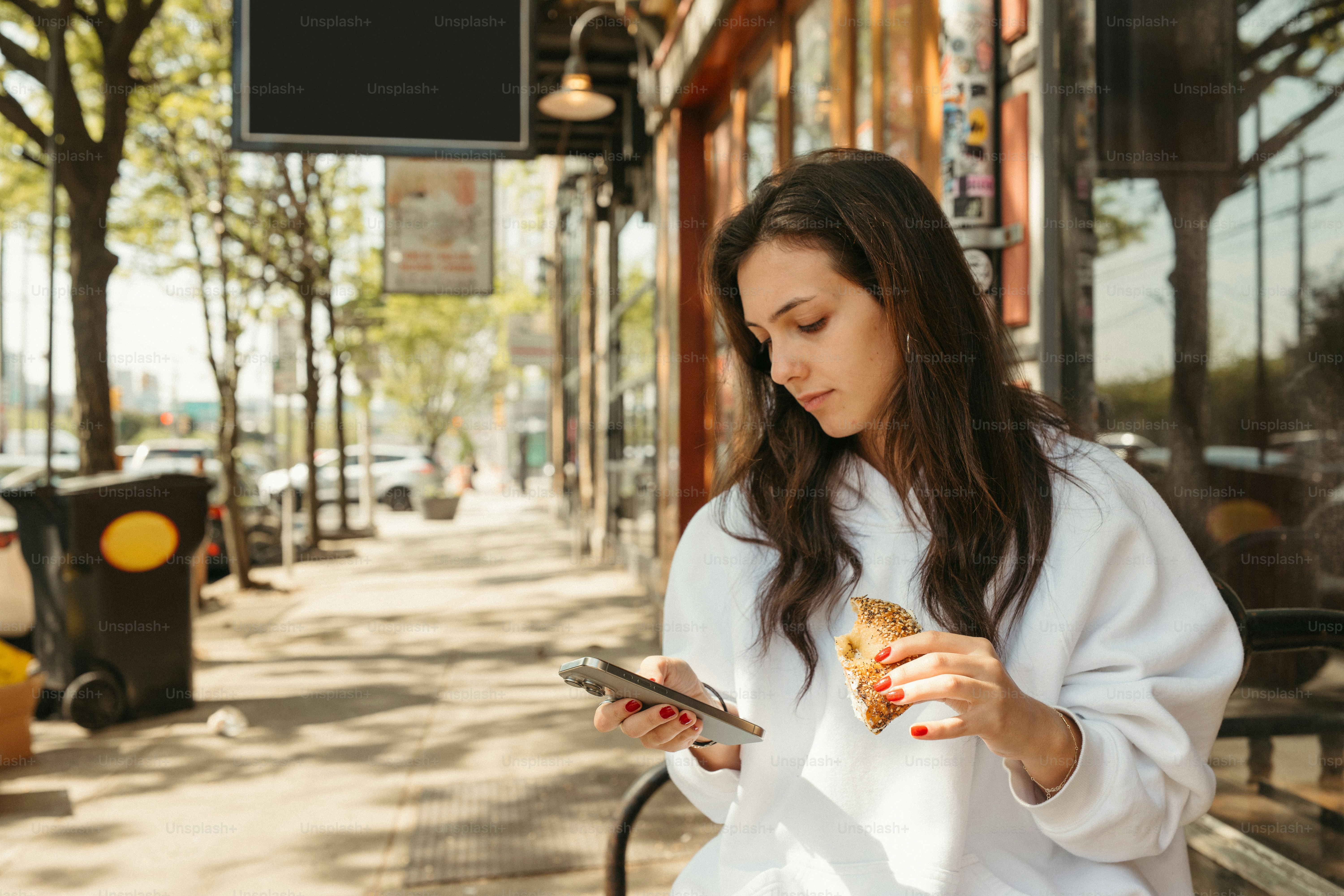 Una donna sta mangiando e usando il suo telefono.