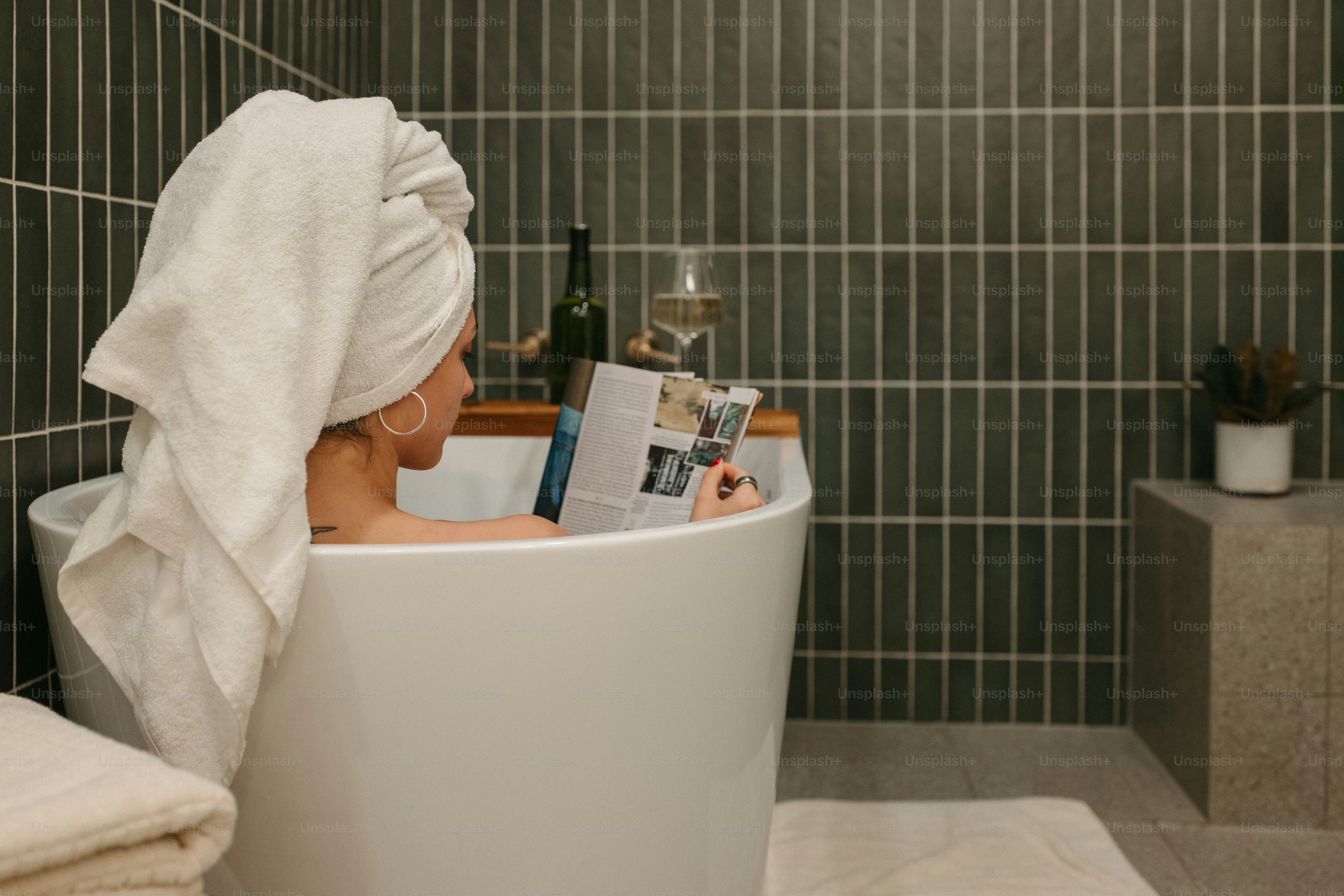 A woman enjoys a relaxing bath with a magazine.