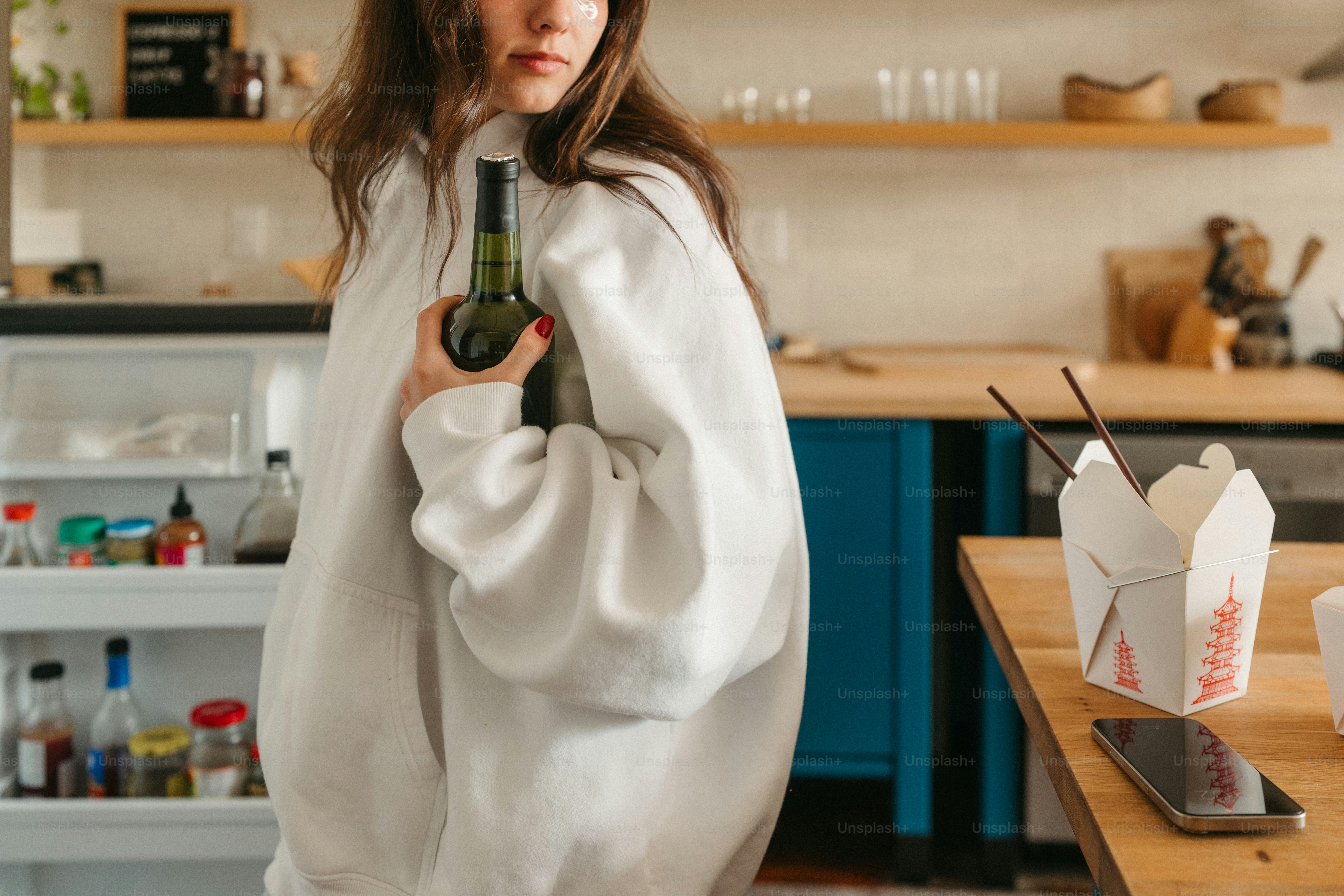 Woman holds a bottle in her kitchen.