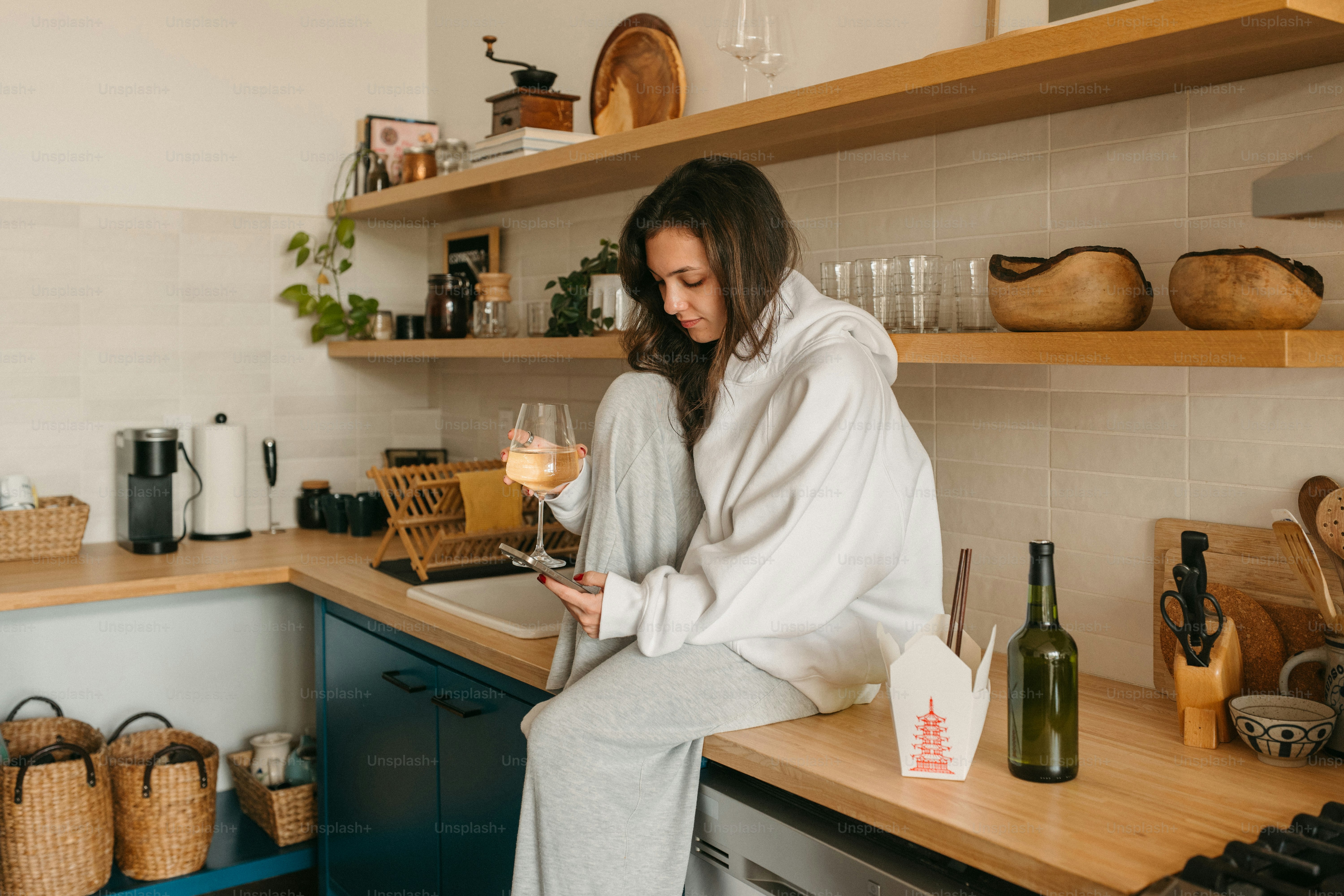 Woman relaxes in the kitchen, enjoying wine.