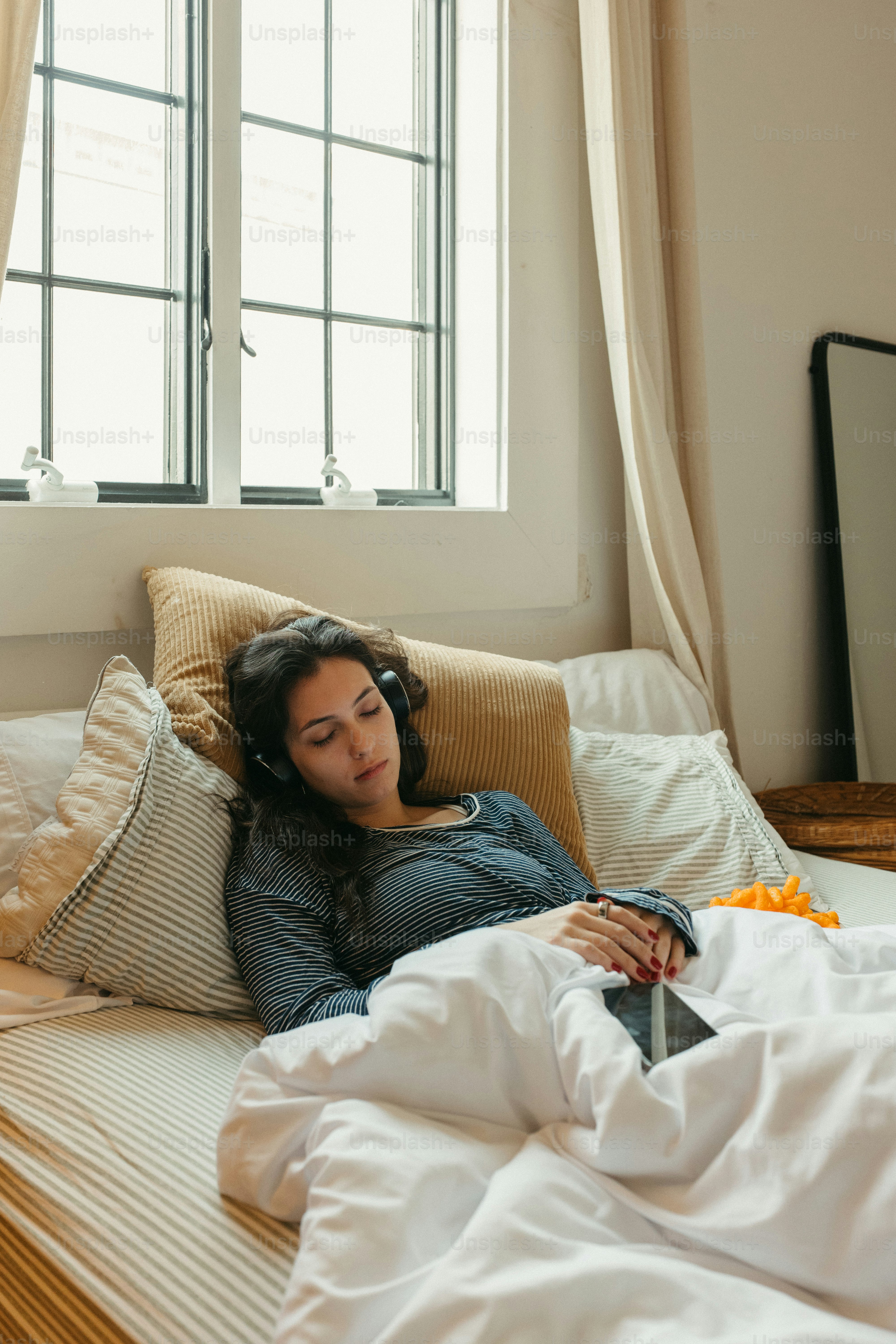 Wanita bersantai di tempat tidur, mendengarkan musik.
