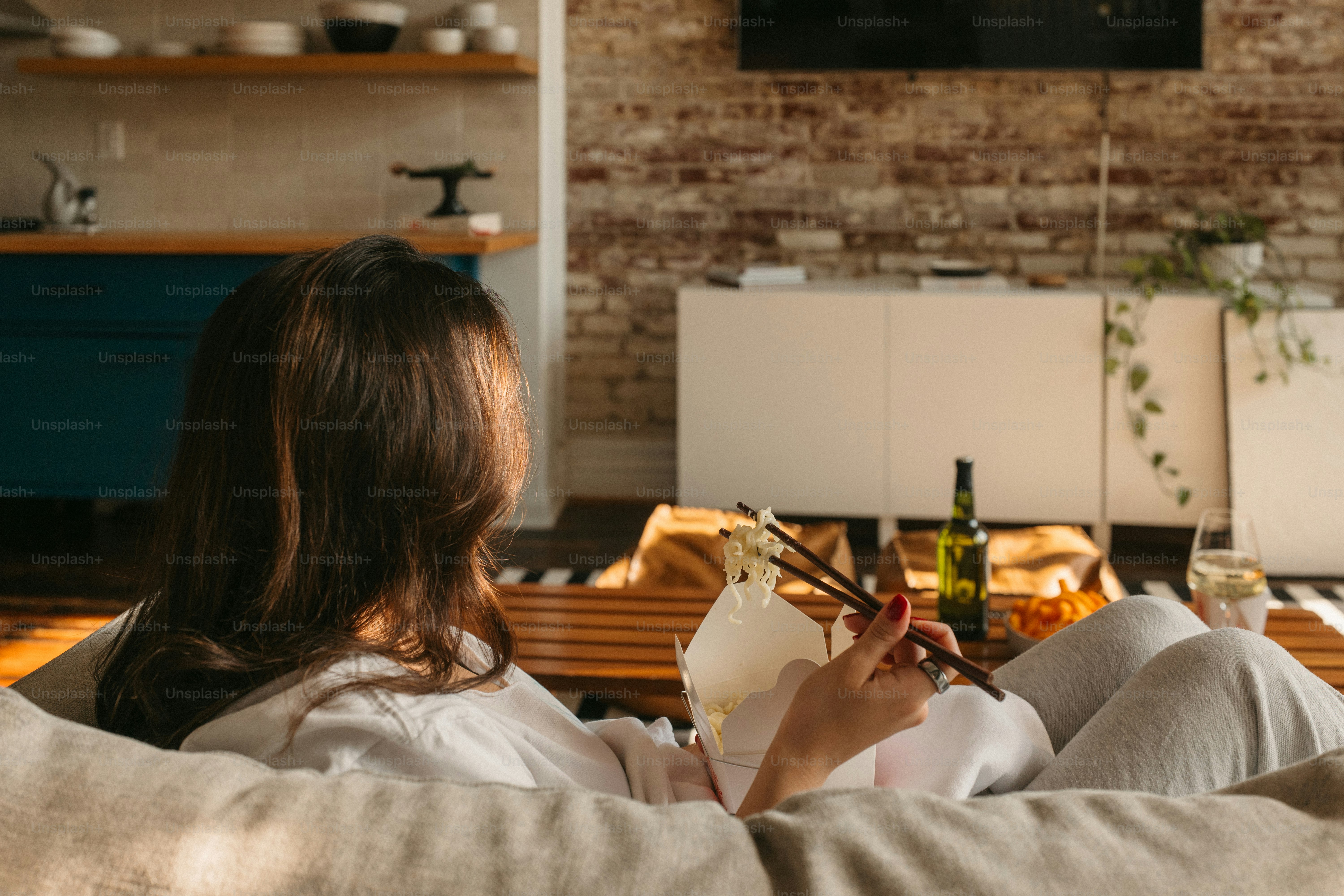 A woman relaxes at home, enjoying sushi.