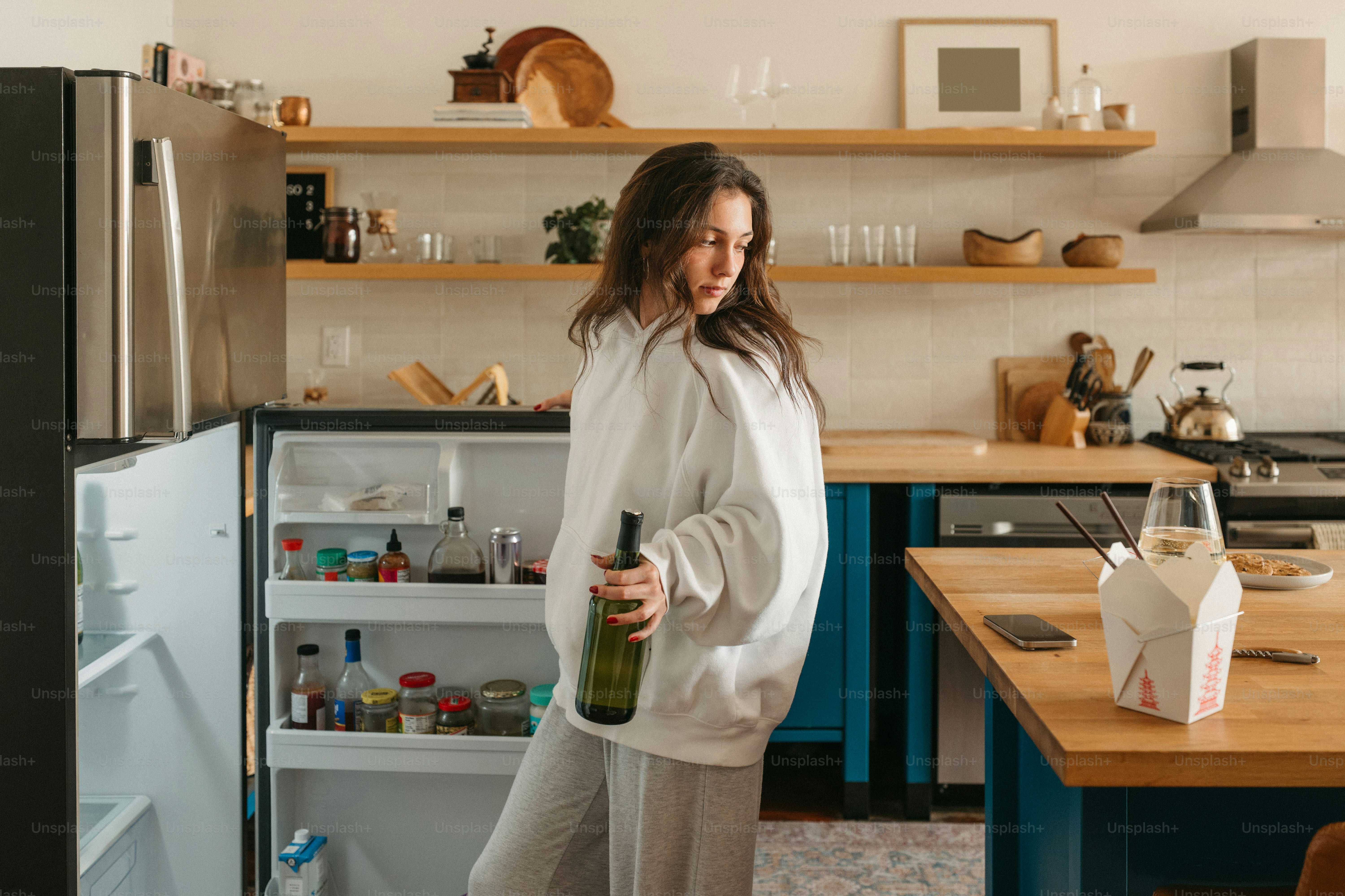 Woman holding wine in a kitchen.