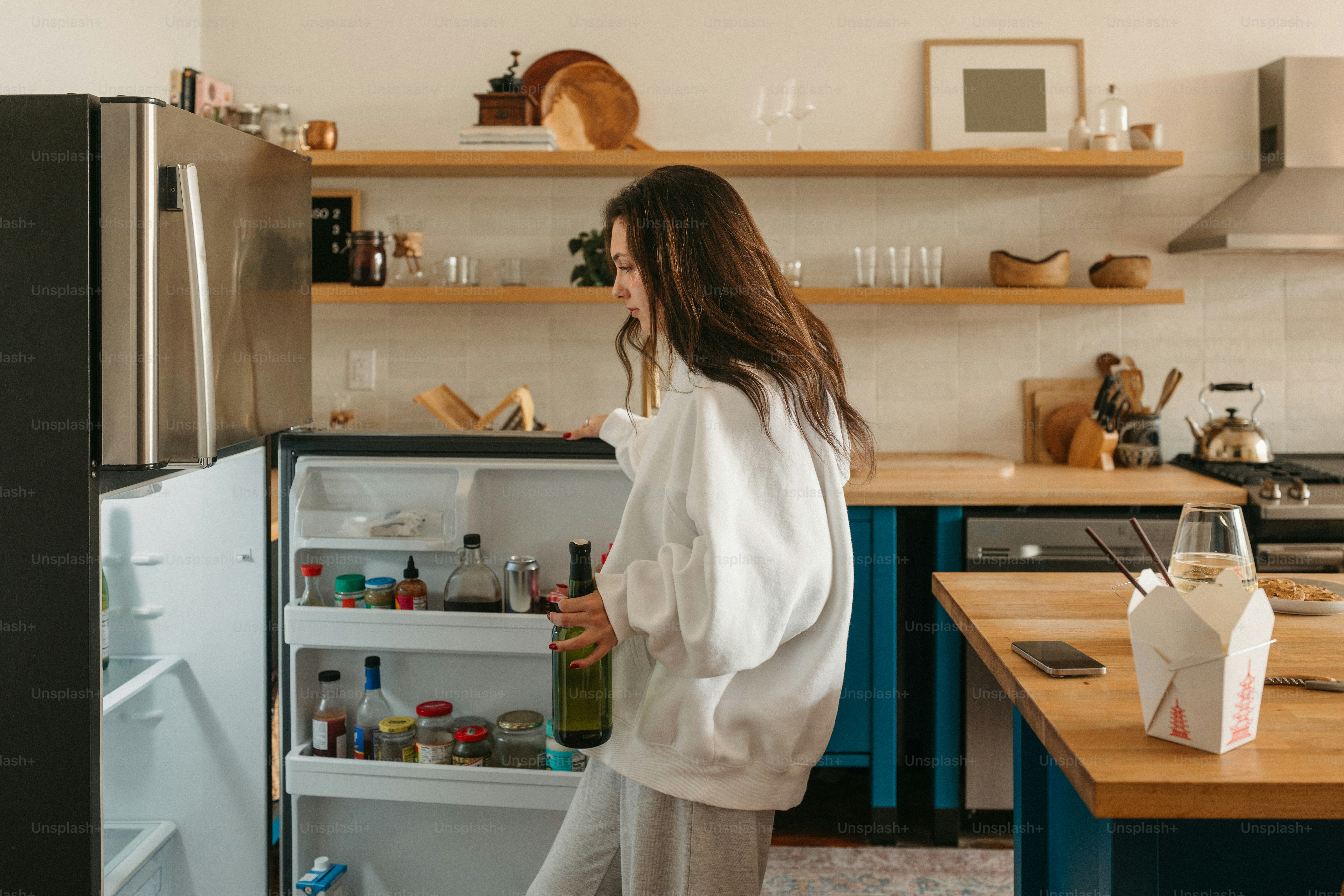 Woman grabs a bottle of wine from the refrigerator.