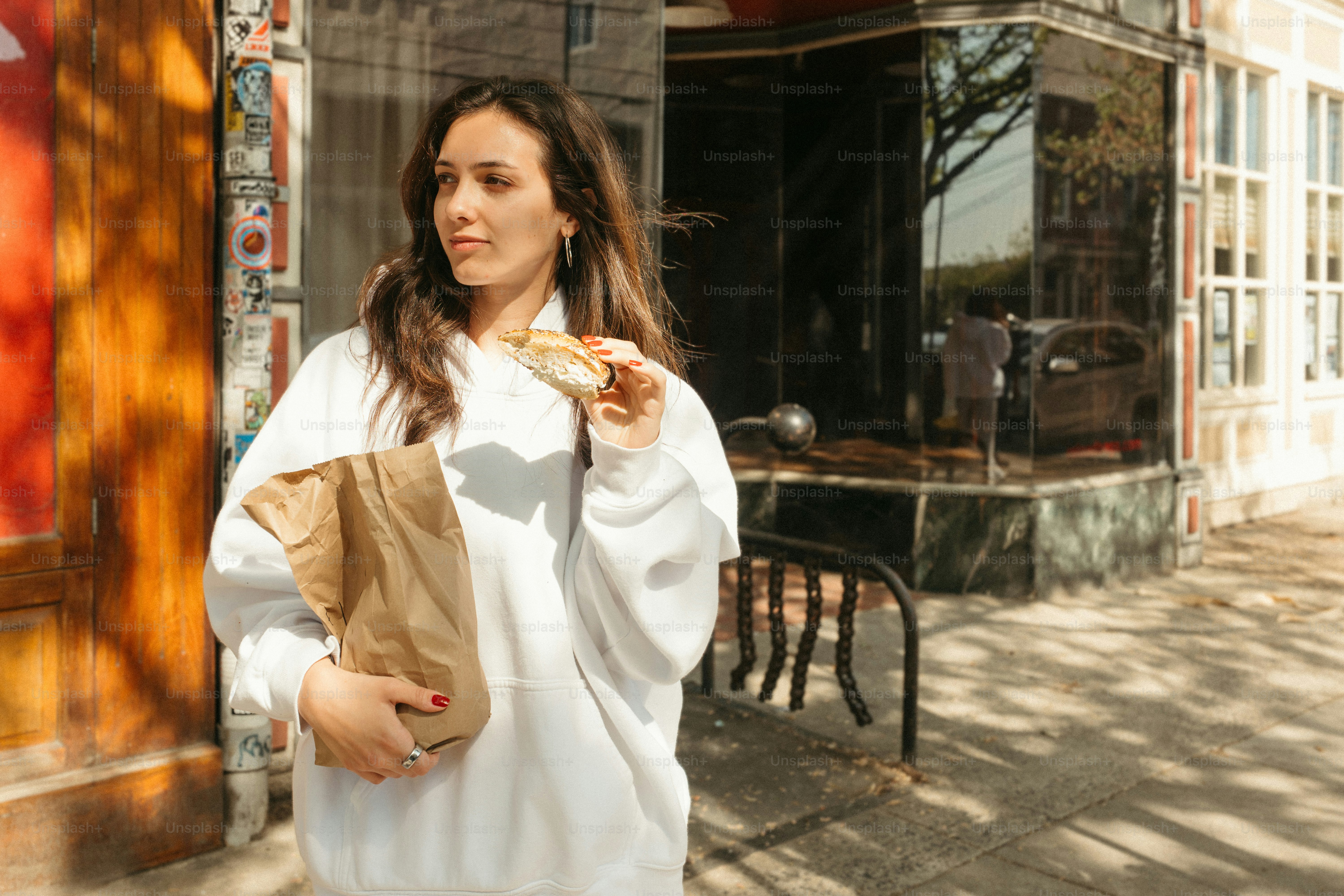 Una mujer con sudadera con capucha disfruta de la comida para llevar en ...