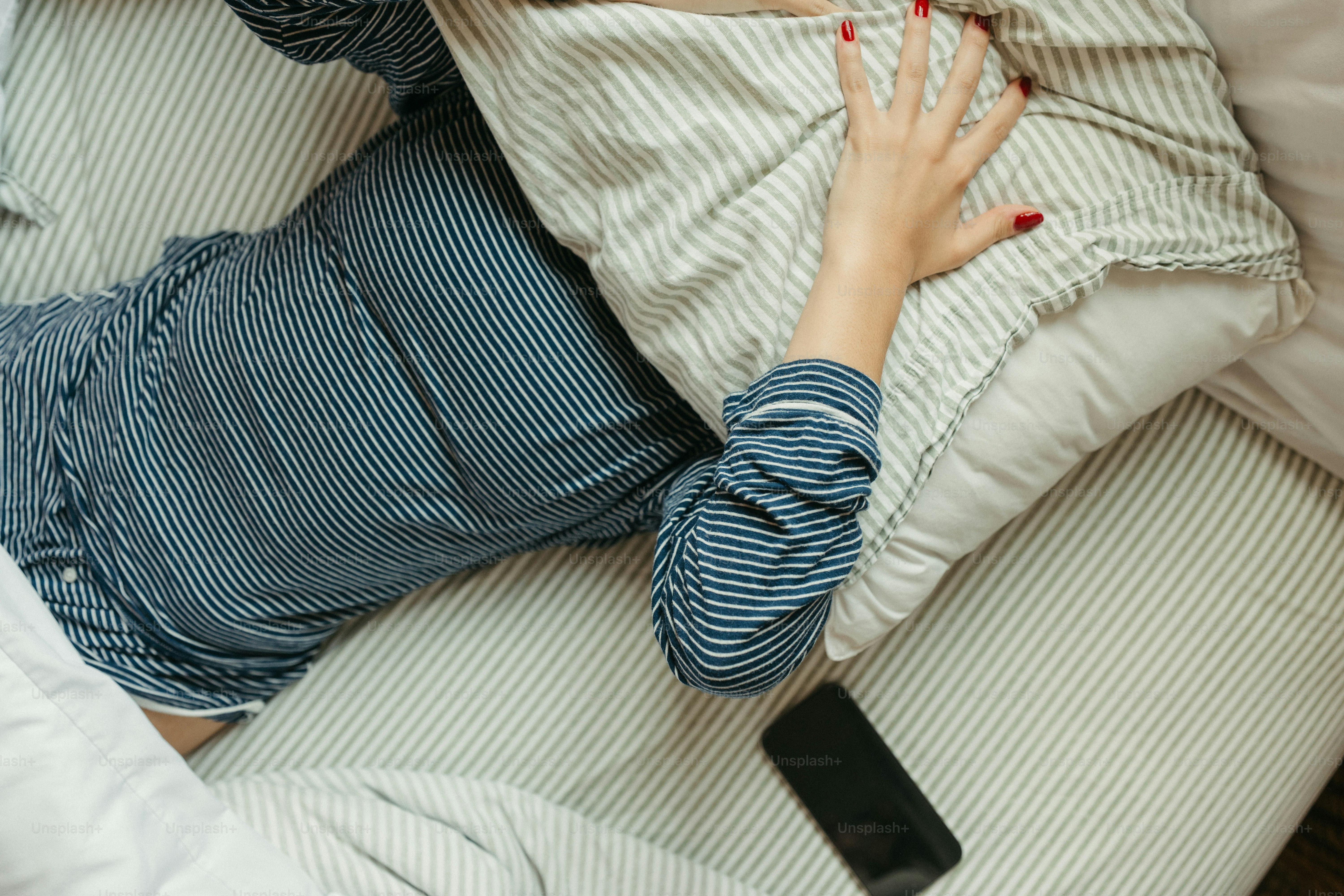 Woman covers her head with a pillow in bed.