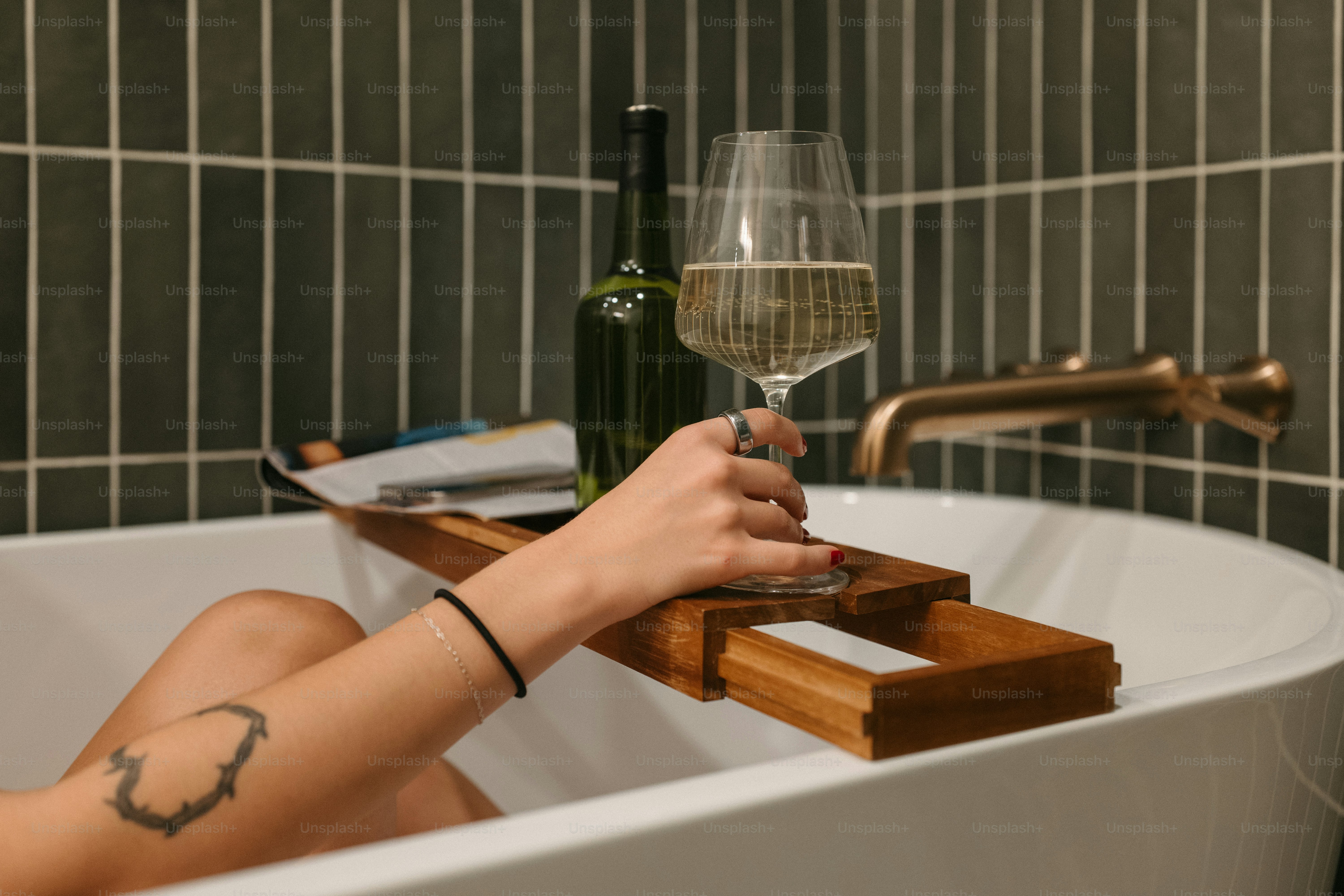 Relaxing in a bathtub with wine and a book.