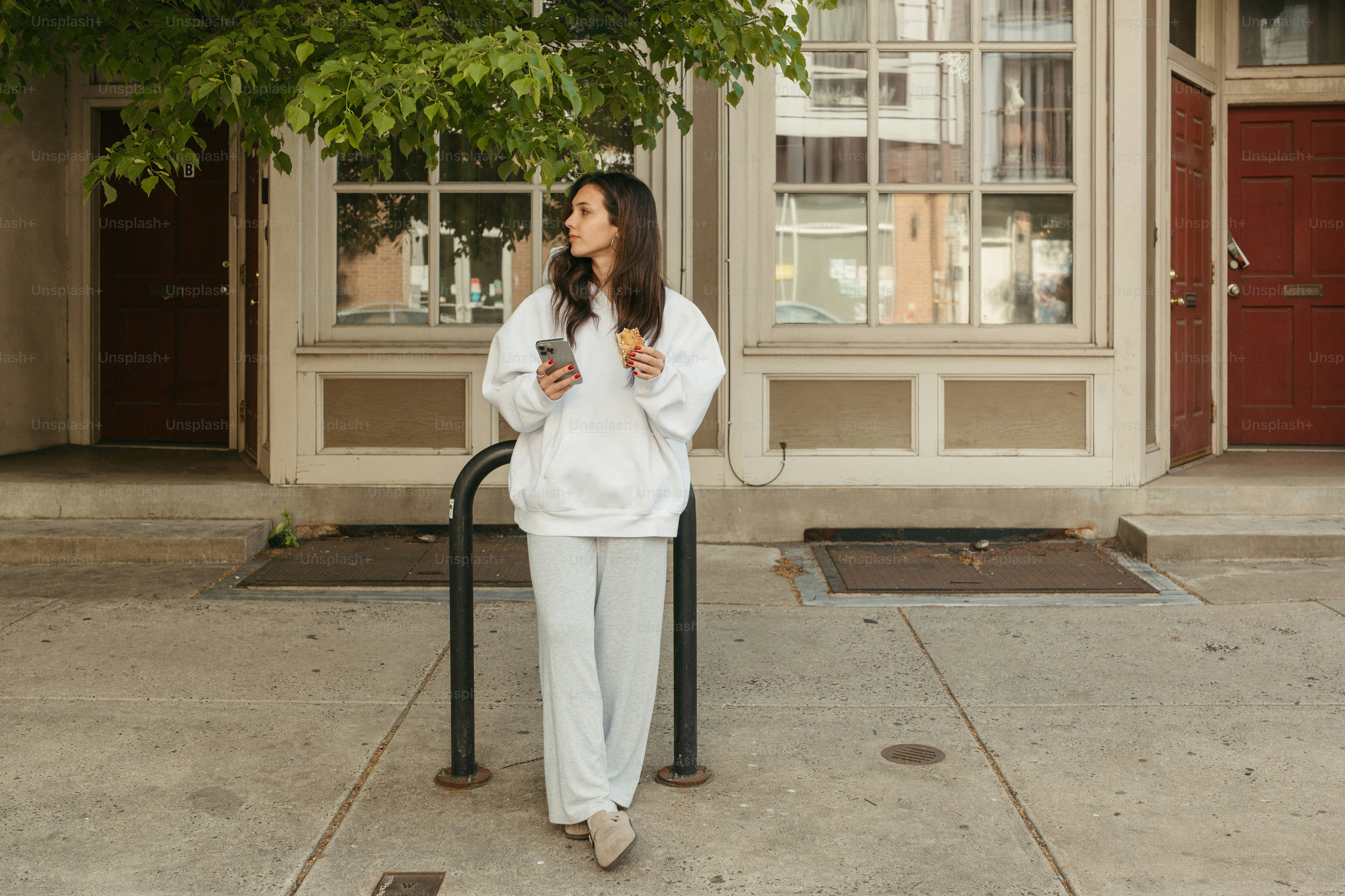 Woman poses outside holding a phone.