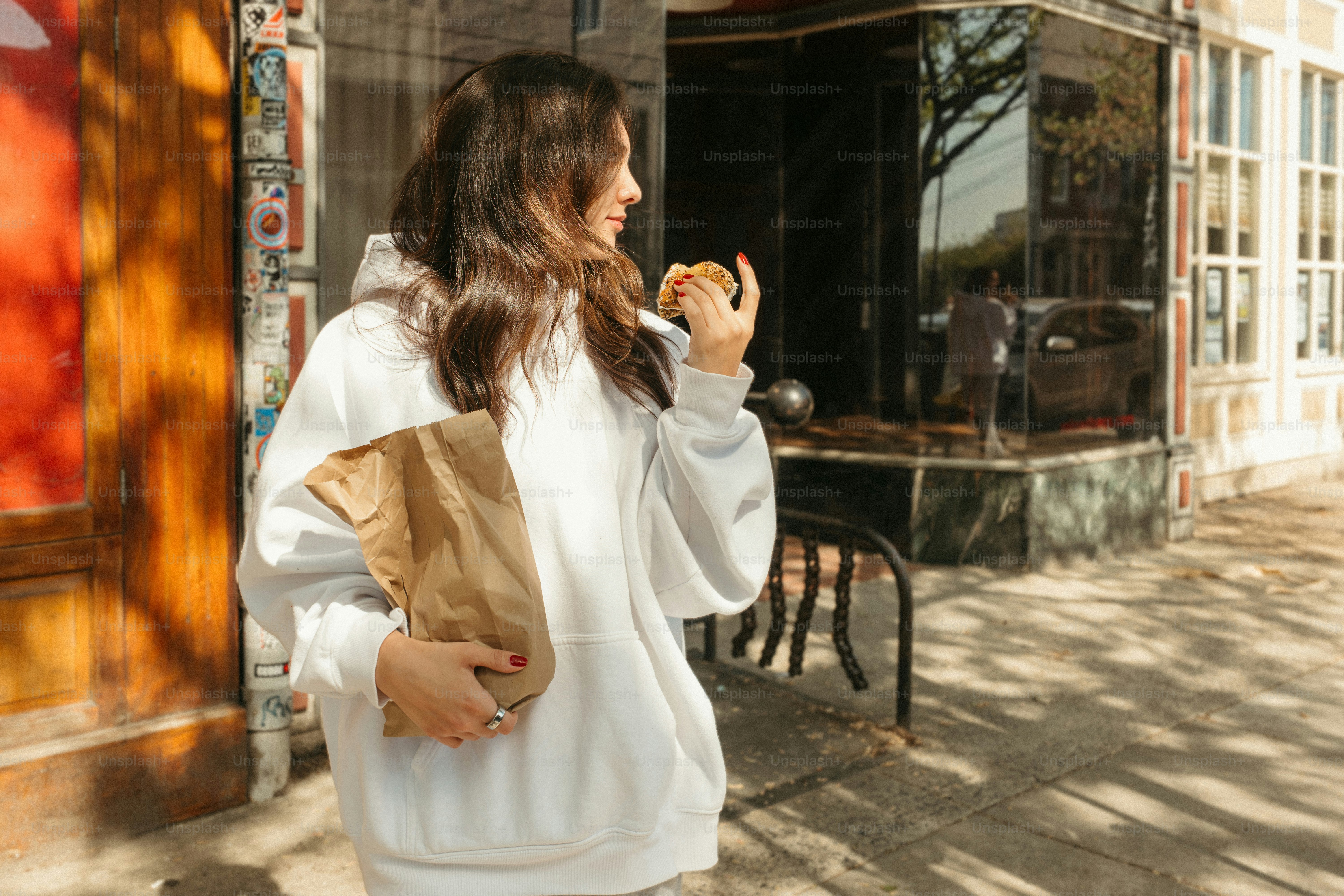Mulher gosta de comida ao ar livre, carregando uma bolsa marrom.