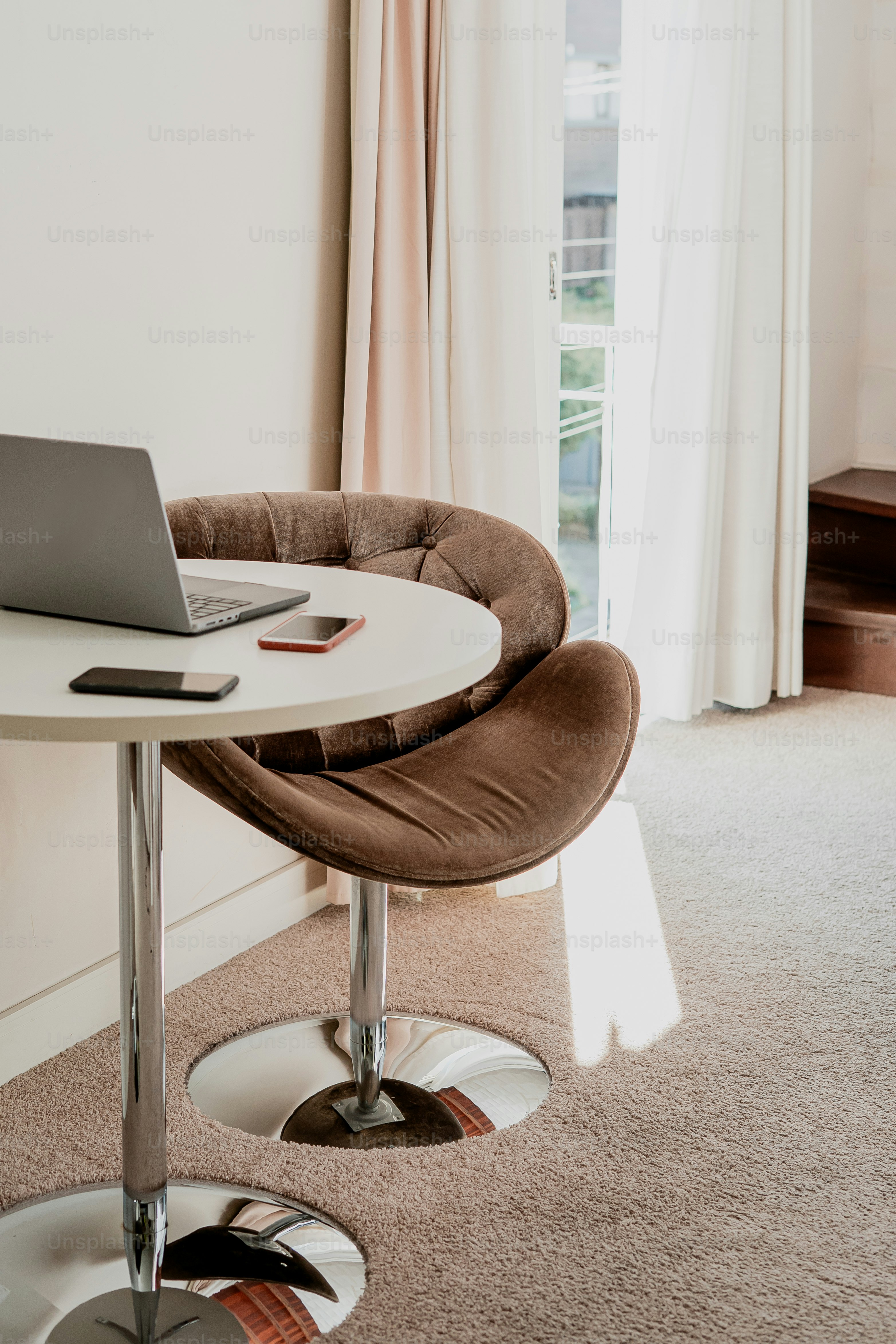 A laptop sits ready on a small round table.