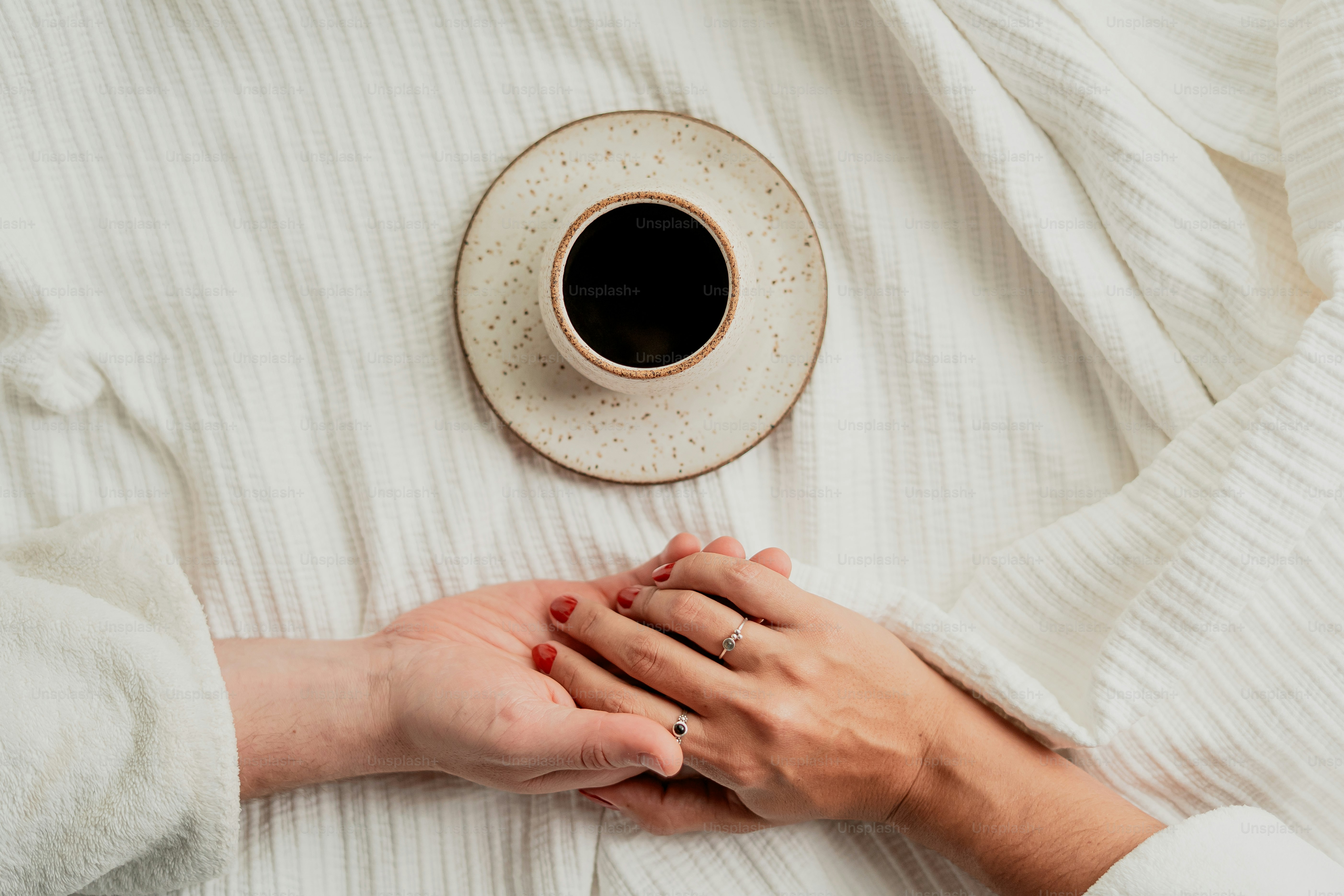 Hands hold under coffee cup.