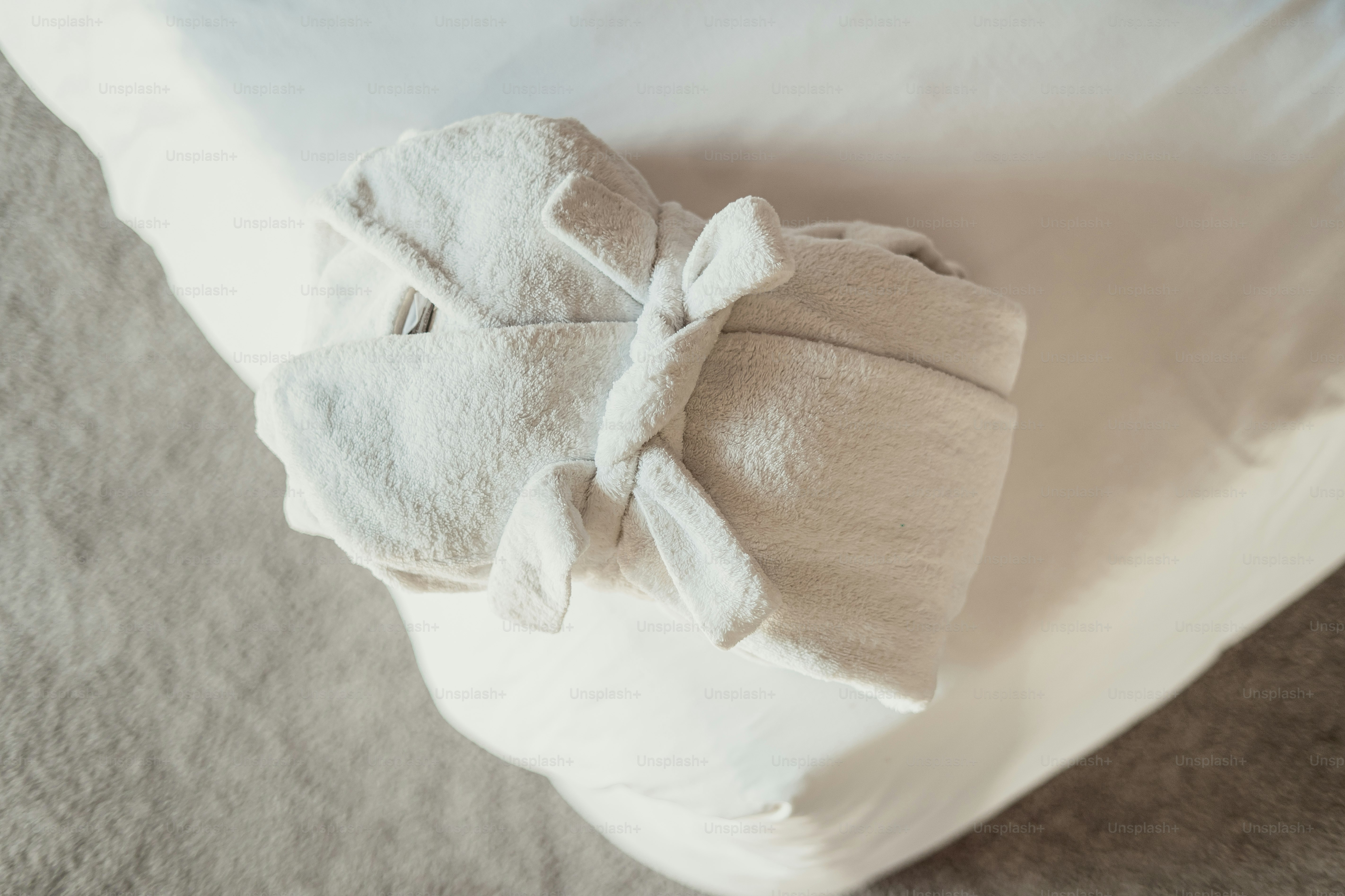 A folded, tied towel rests on a bed.