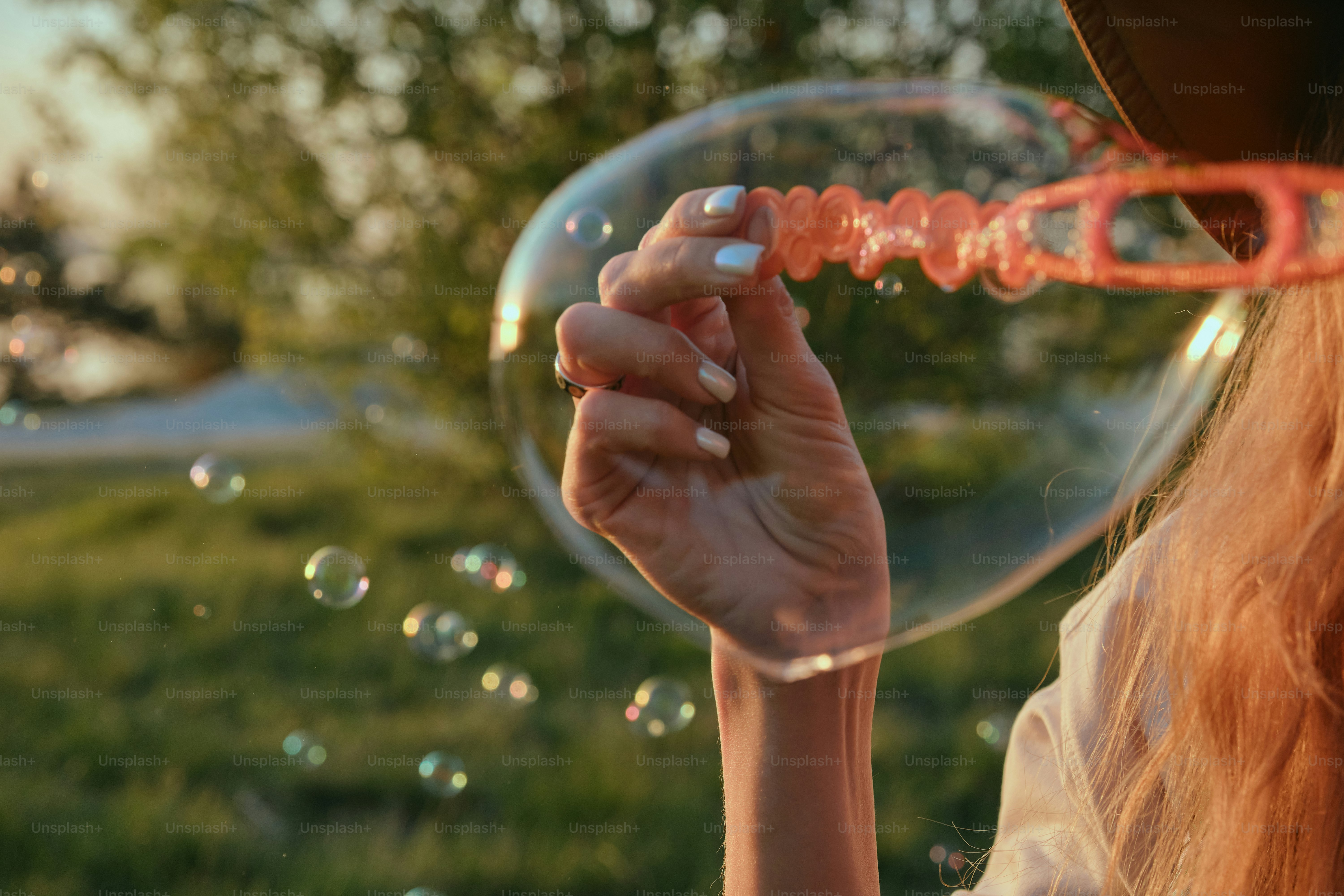 A woman blows bubbles outside on a sunny day.