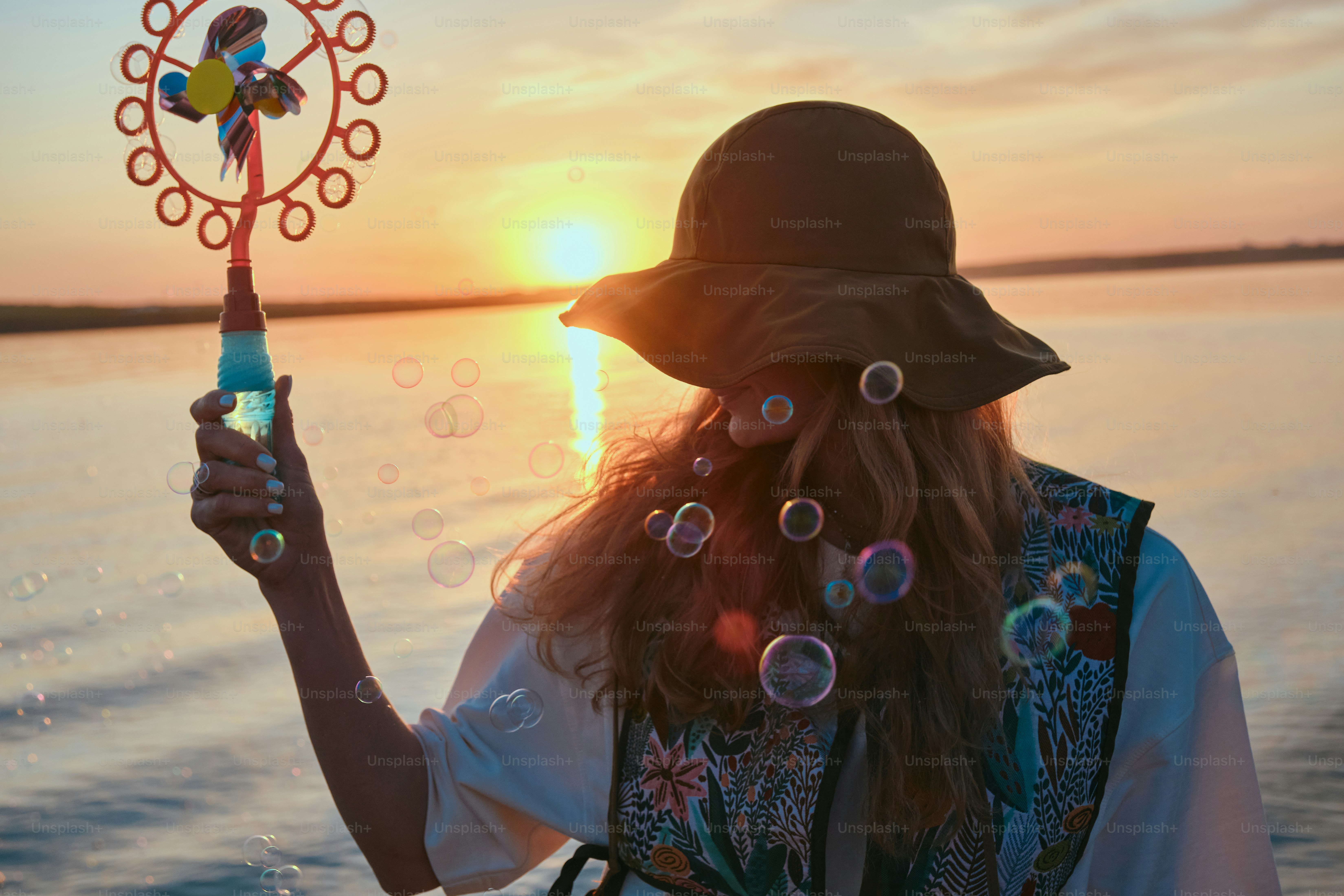 La donna soffia bolle in un tramonto.