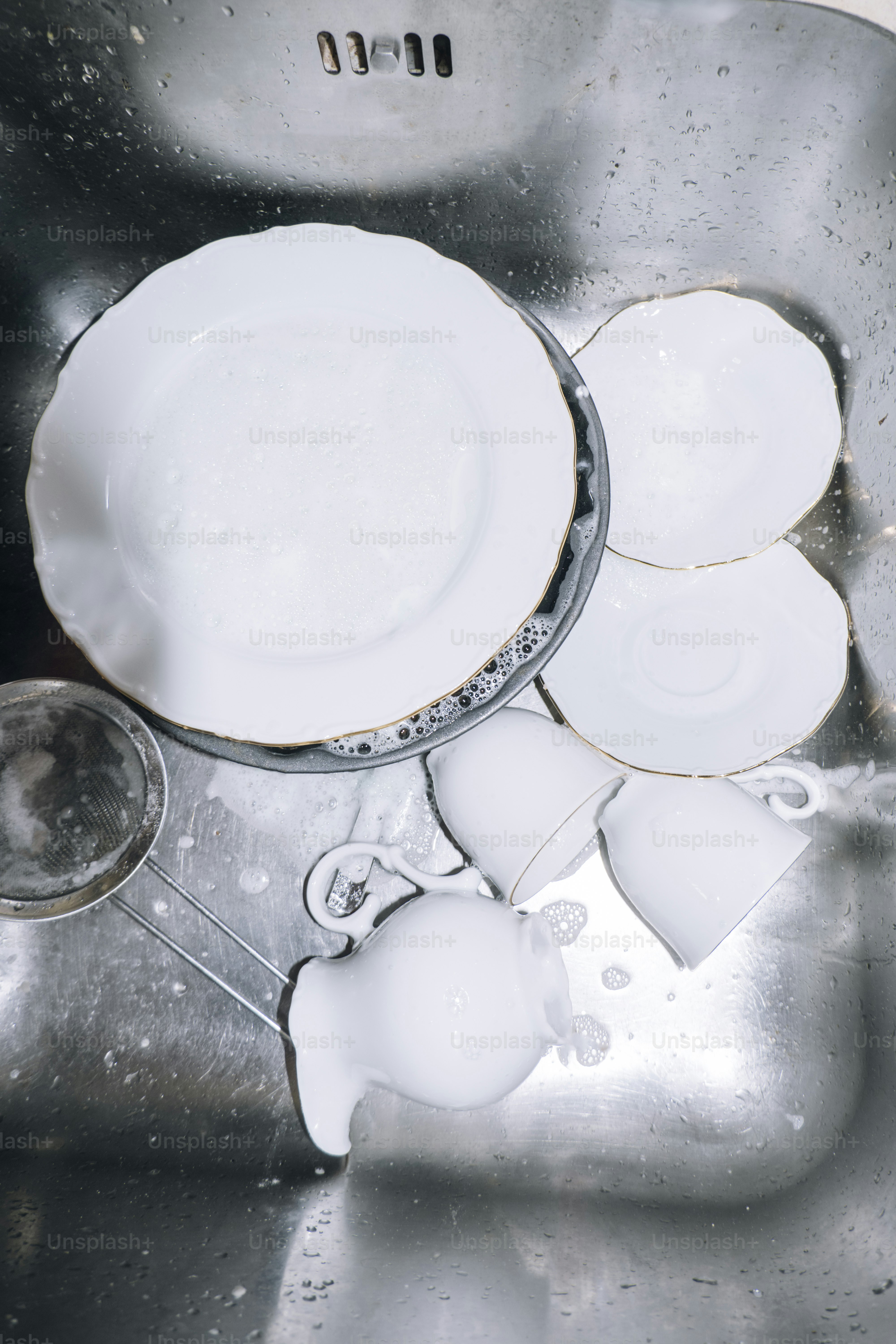 Dishes are in a kitchen sink, ready to be washed.