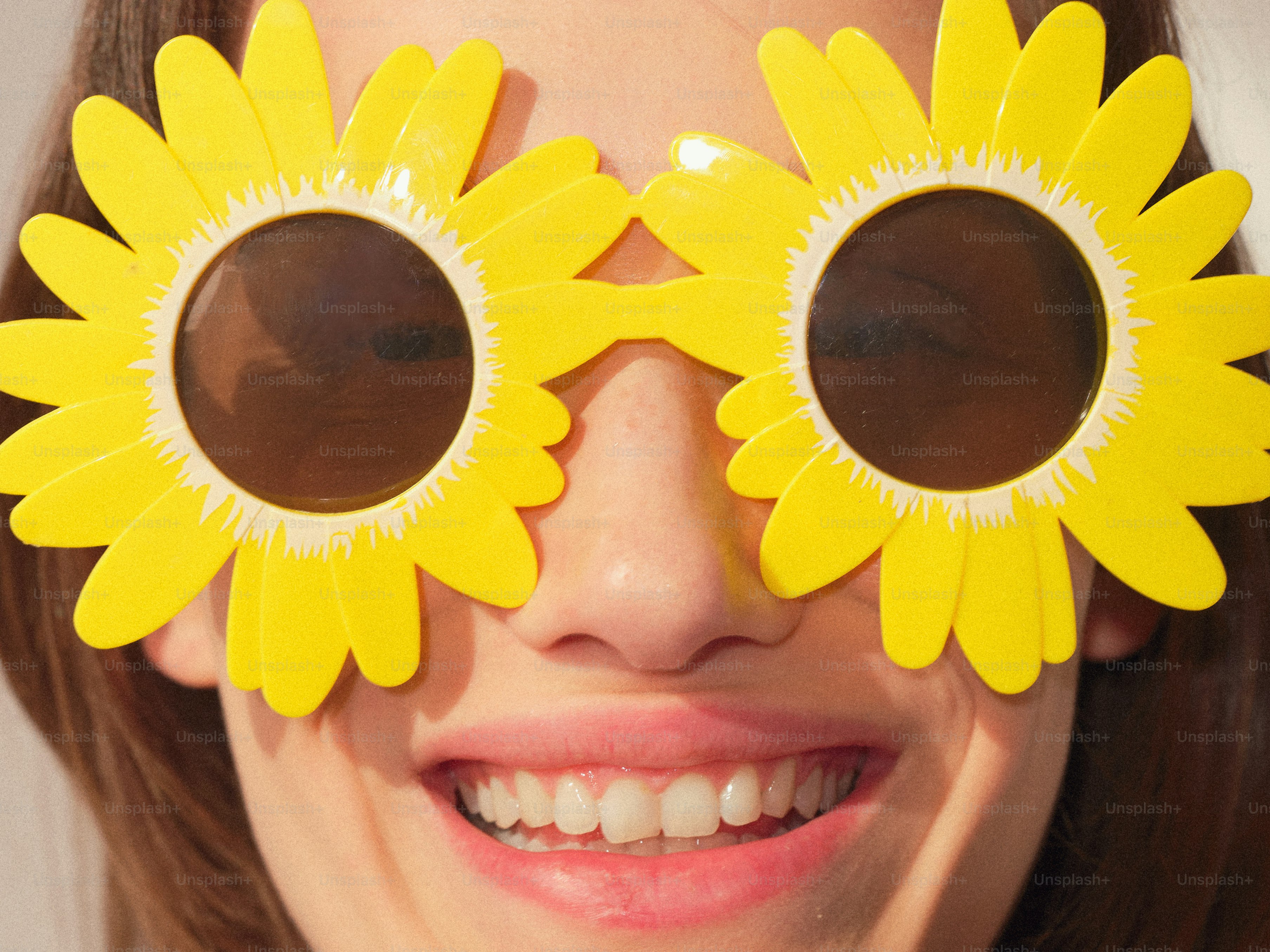 Una persona sorride indossando occhiali da sole a forma di fiori.